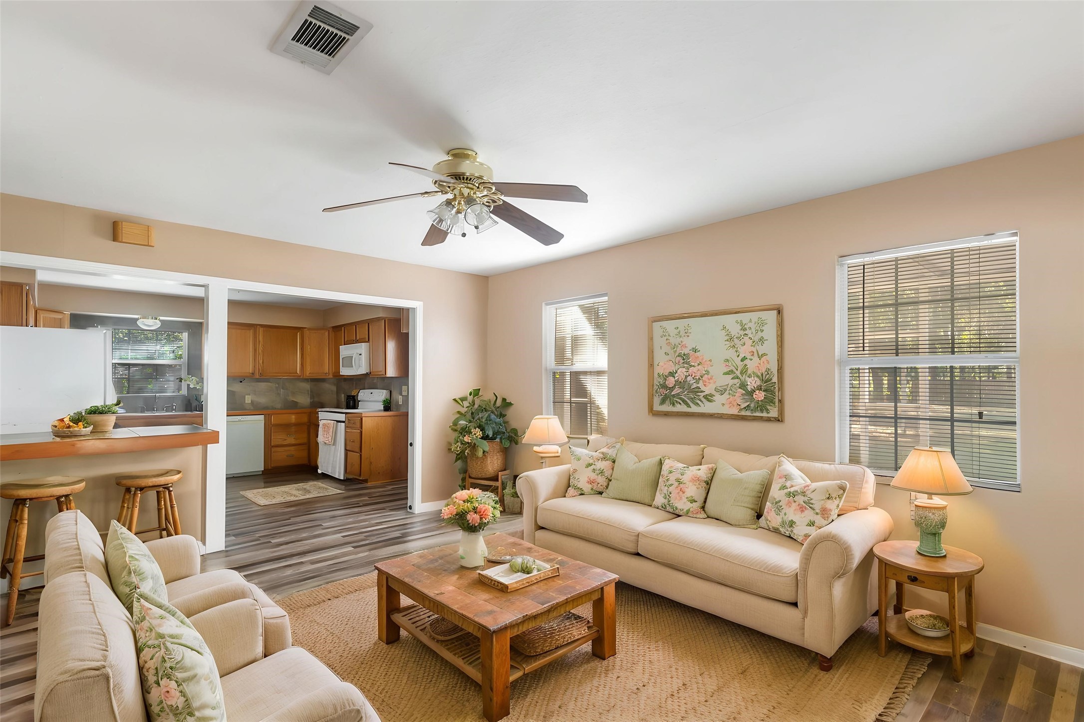 Comfortable living area with natural light, wood-look flooring and a ceiling fan. A great opportunity to personalize a home with room to make it your own. (This photo is virtually staged.)