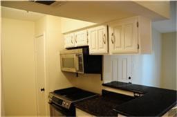 Cozy kitchen with white cabinets, black countertops, and a built-in microwave. Compact layout ideal for efficiency.