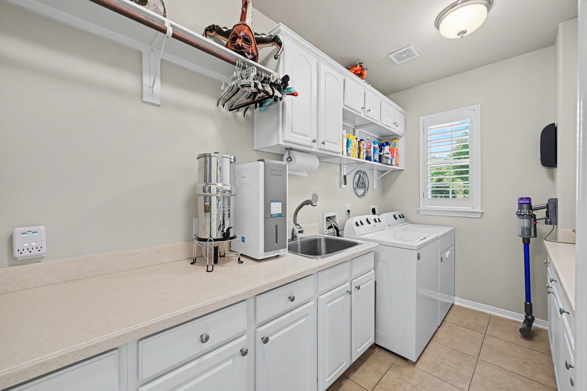 Spacious utility room with sink, extensive cabinetry, and convenient workspace.