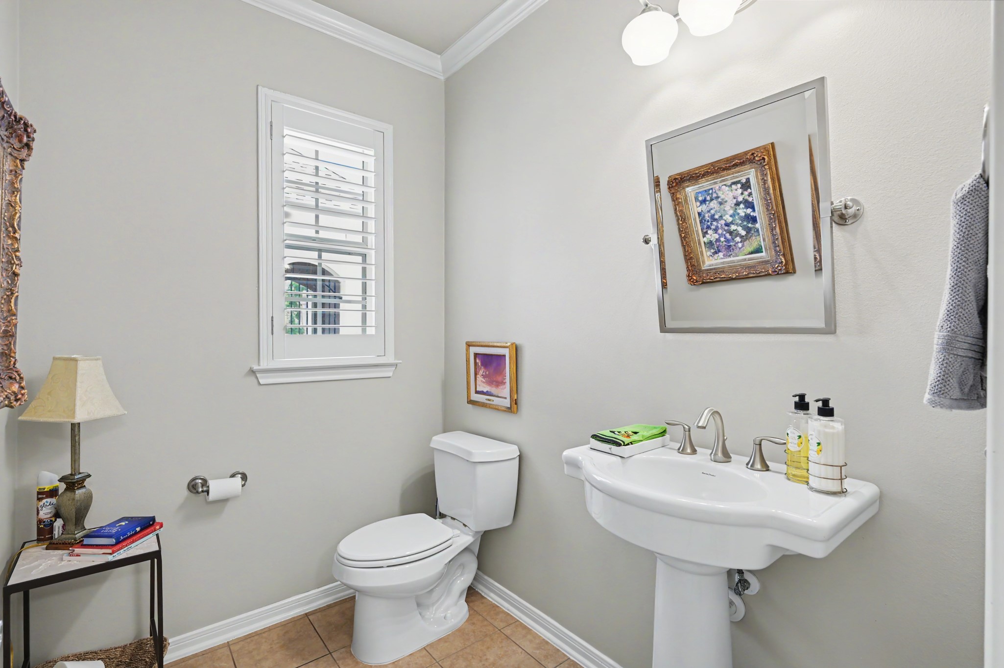 Convenient powder bath featuring a pedestal sink and plantation shutters.