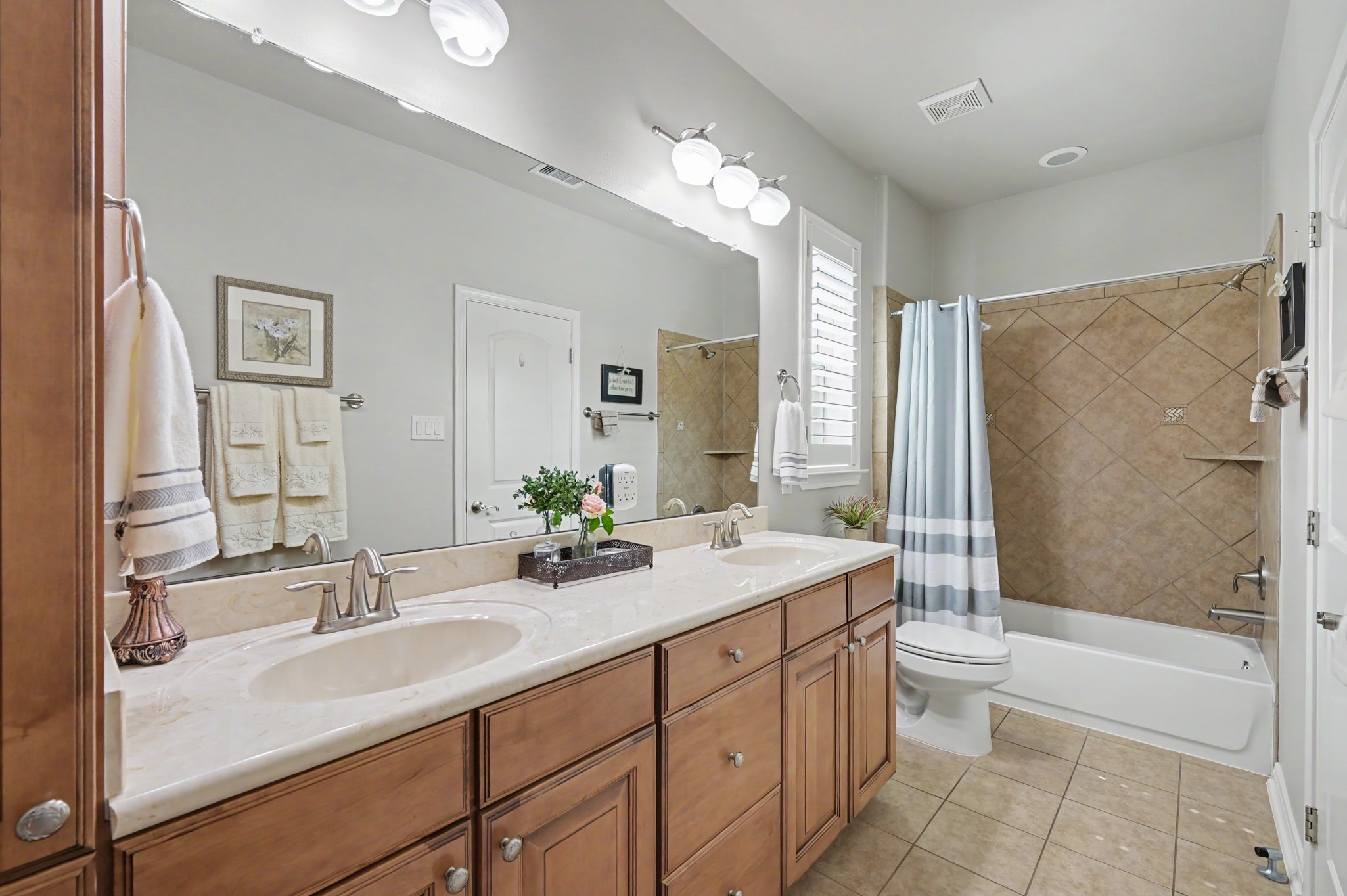 Beautifully appointed guest bathroom with dual sinks and tub-shower combination.