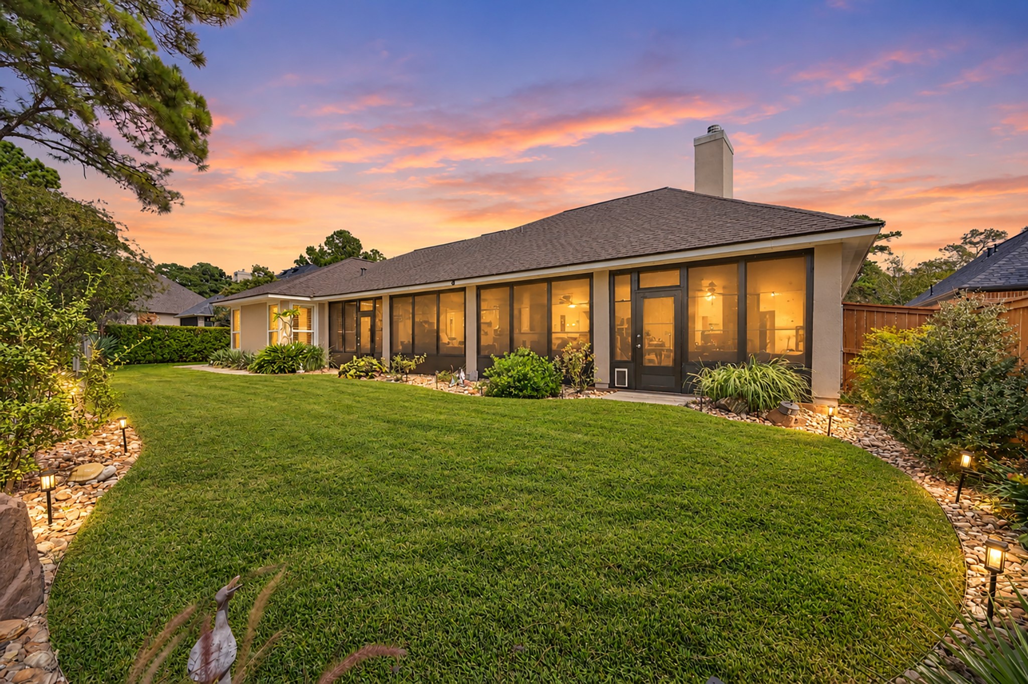 Gorgeous sunset highlights the expansive screened porch and beautifully landscaped backyard.
