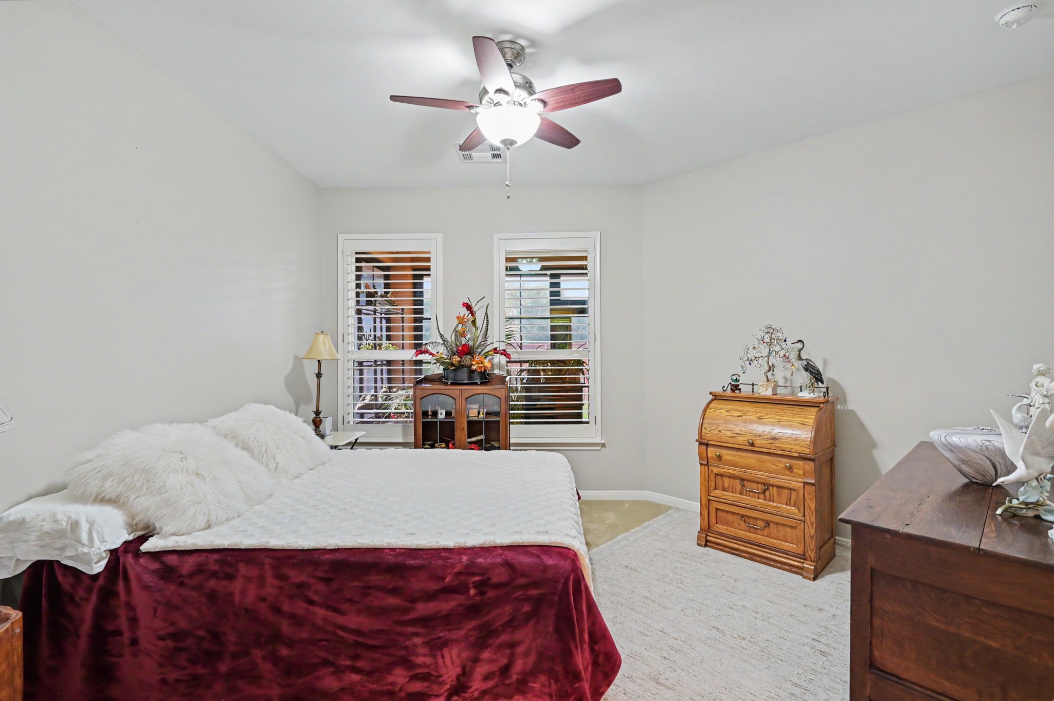 Comfortable guest bedroom with ceiling fan and attractive natural light.