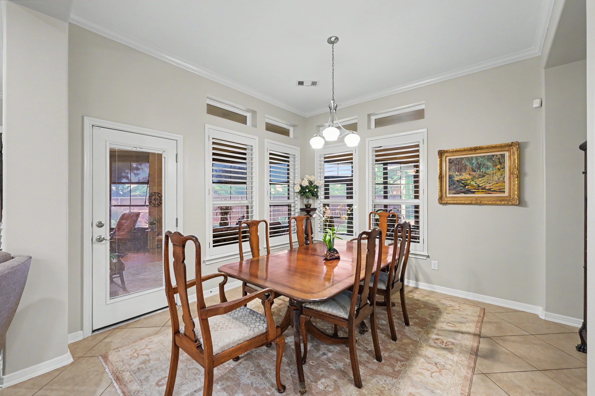 Elegant dining area with plantation shutters and lovely backyard views.