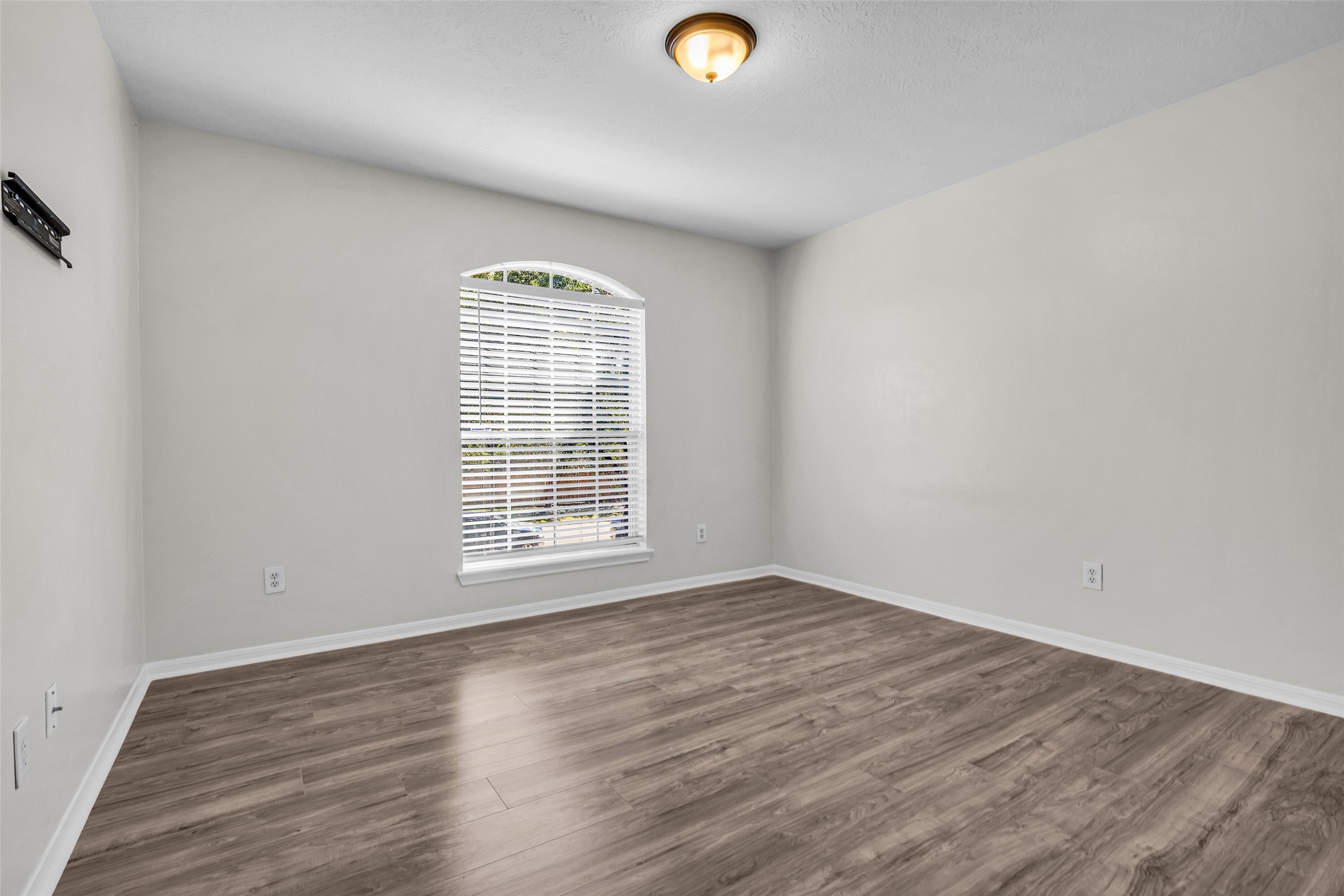 An upstairs bedroom with an arched window, ideal as a home office or hobby room.