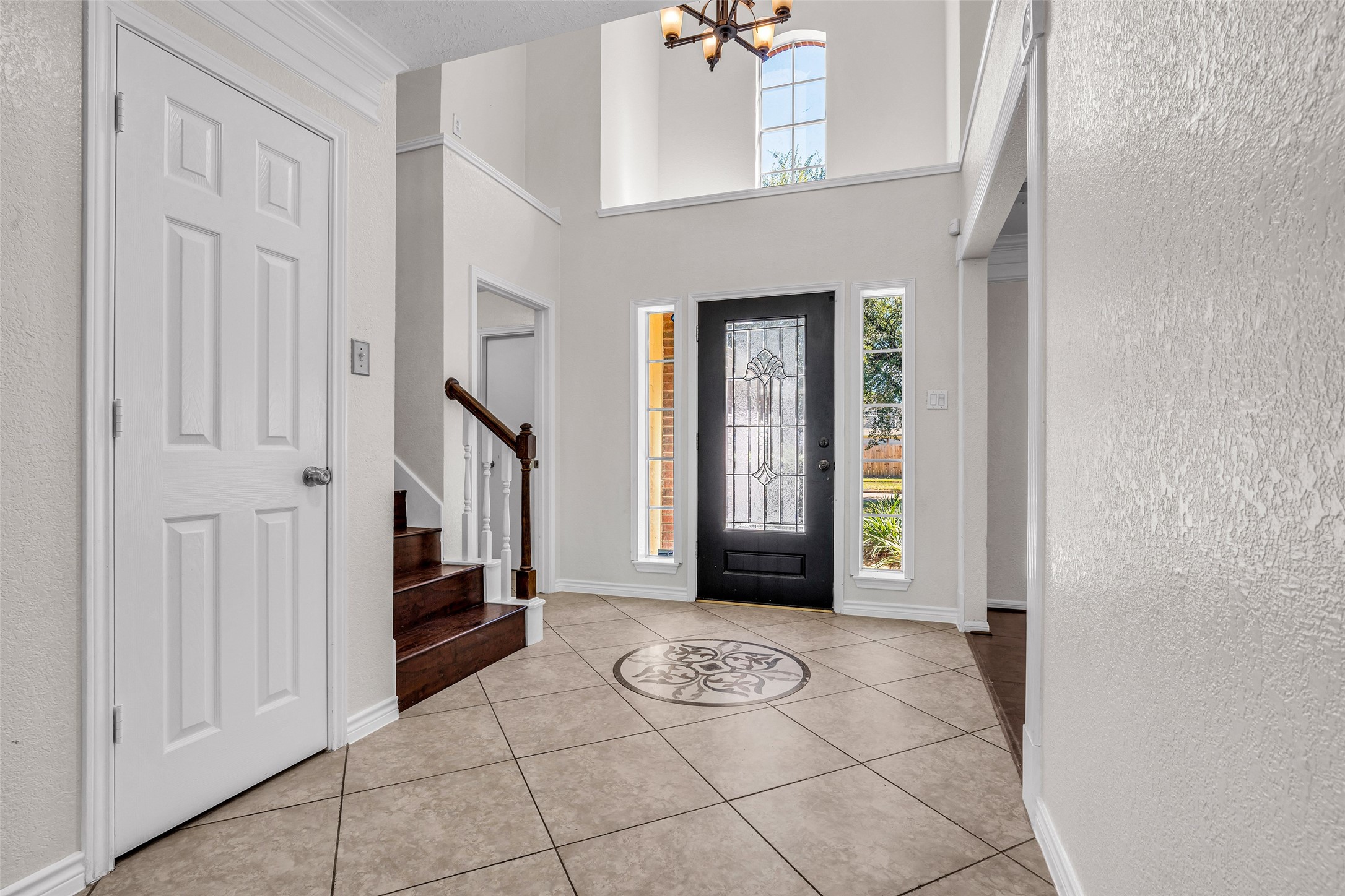 Step inside to a soaring entry with a decorative glass front door and tile medallion inlay.