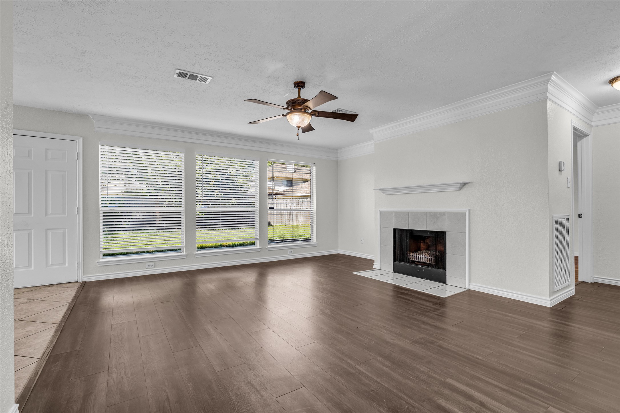 Gather around the tiled fireplace in a living room lined with windows to the backyard. Gather around the tiled fireplace in a living room lined with windows to the backyard.
