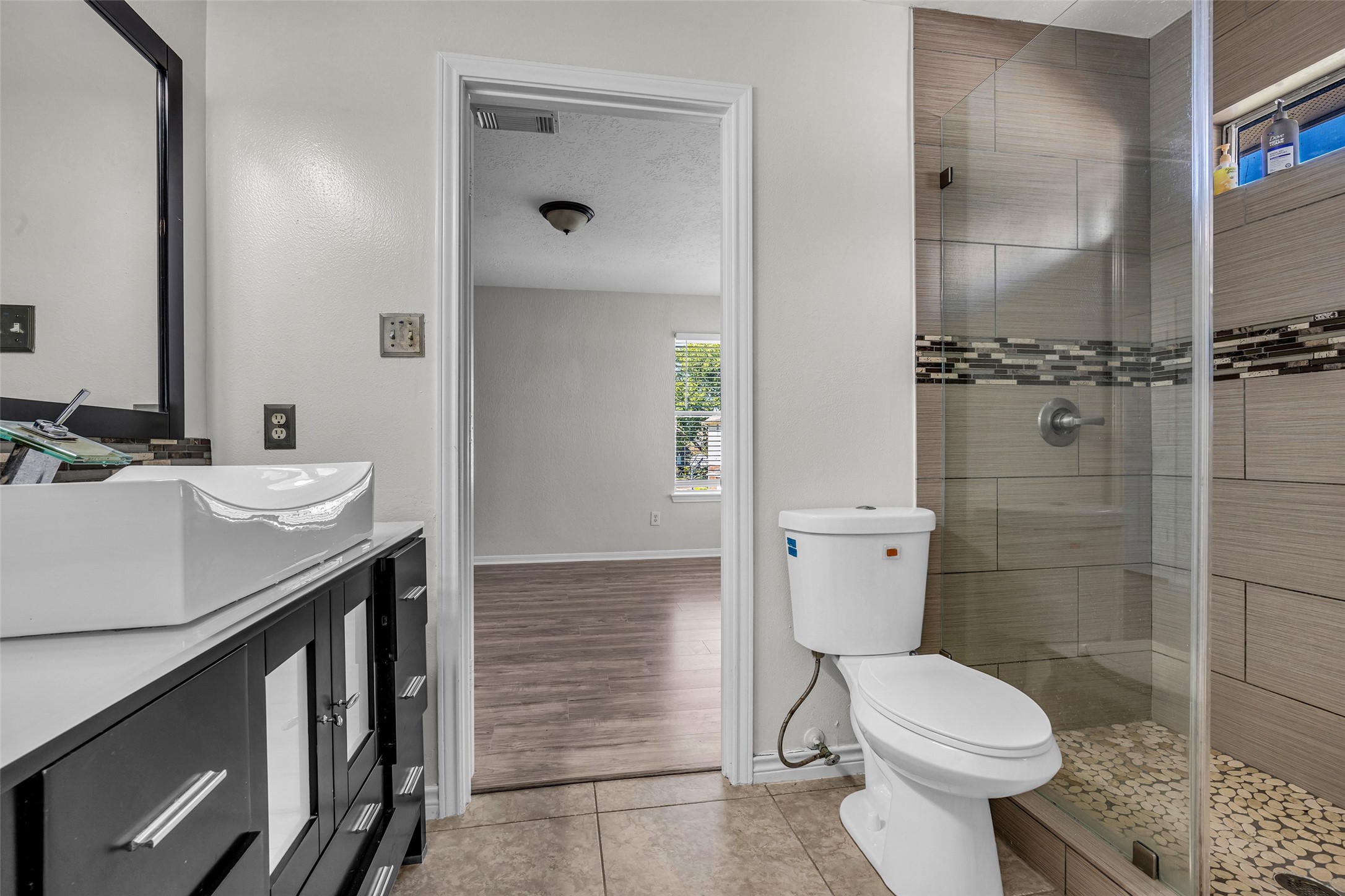 A full bath with a vessel sink, tiled walk-in shower and modern vanity.