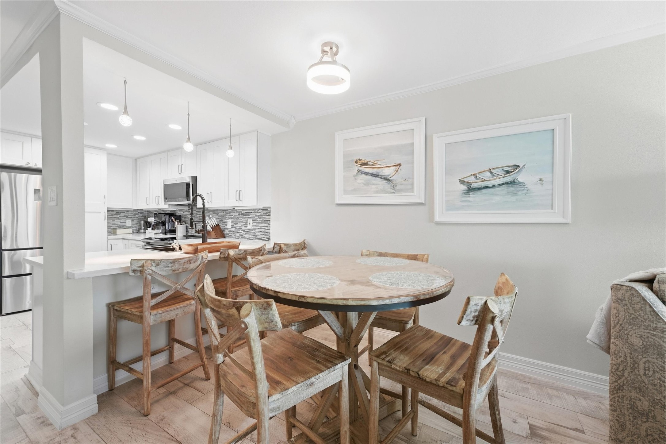 Charming dining area with a rustic wooden table set, seamlessly connected to a modern kitchen featuring sleek cabinetry, stainless steel appliances, and stylish pendant lighting.