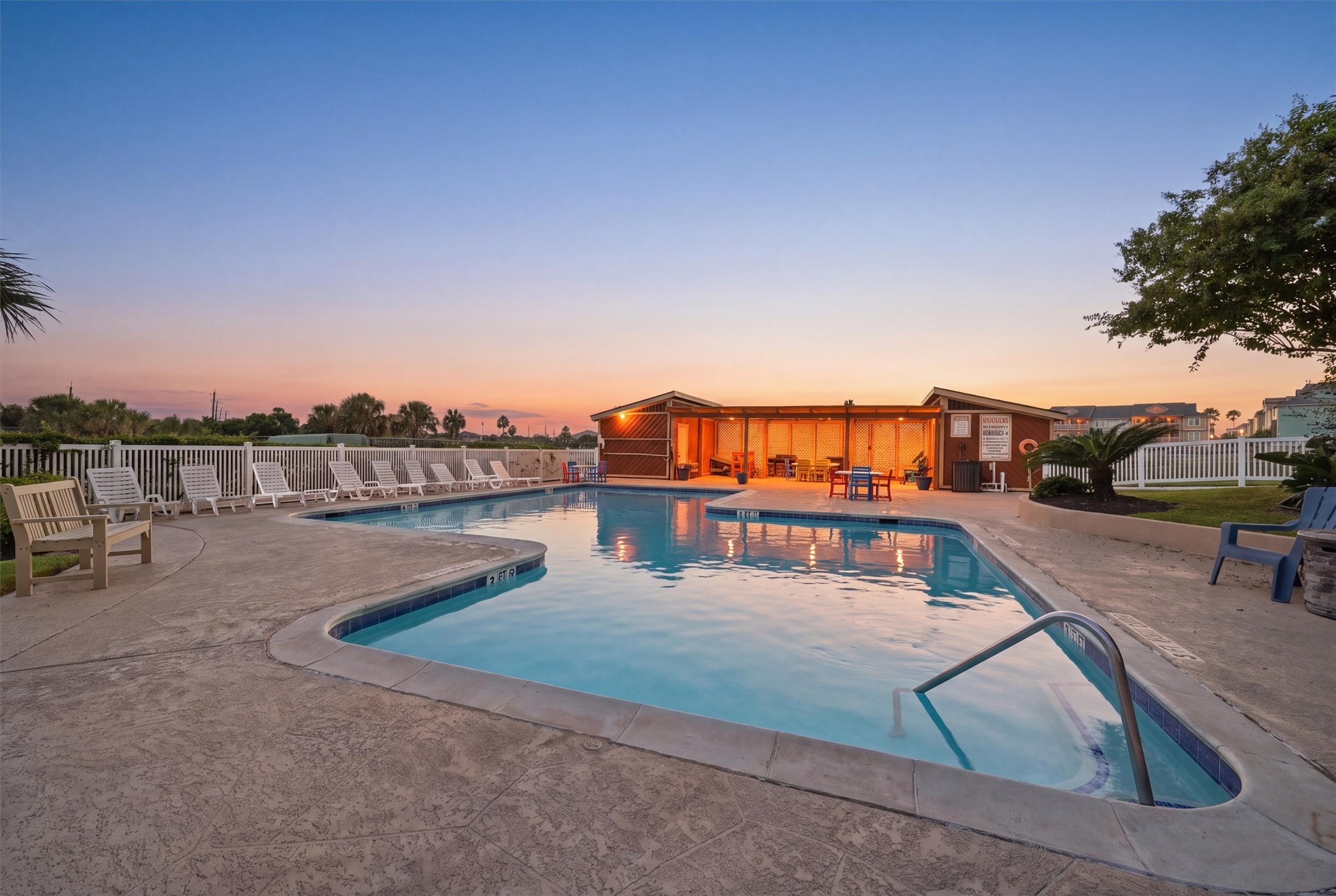 Relax and unwind in this inviting outdoor pool area, complete with ample seating and a picturesque sunset backdrop, perfect for evening gatherings.