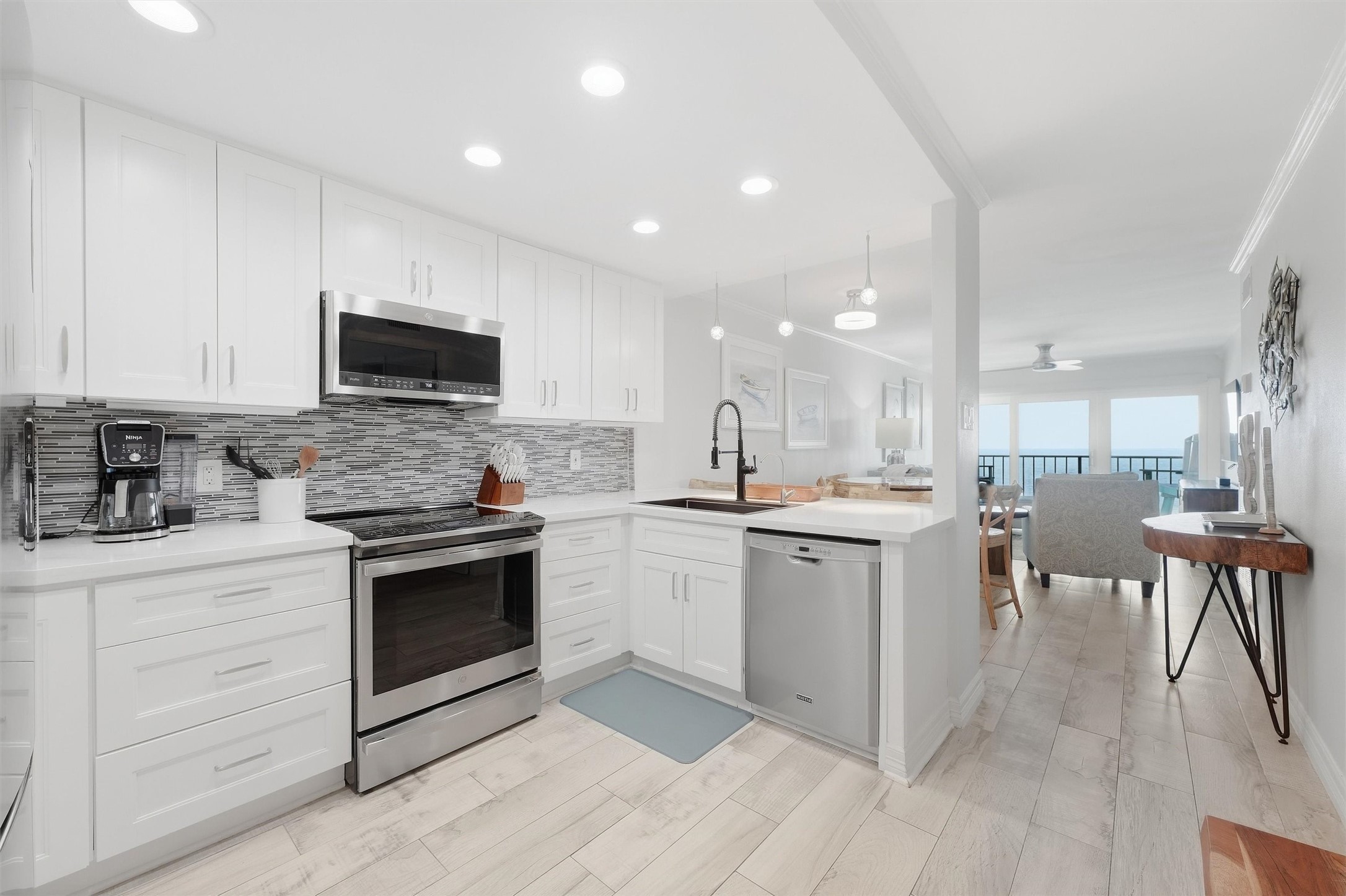 Sleek and modern kitchen with stainless steel appliances, bright white cabinetry, and a stylish tile backsplash. The space flows seamlessly into the open living area, perfect for entertaining. Sleek and modern kitchen with stainless steel appliances, bright white cabinetry, and a stylish tile backsplash. The space flows seamlessly into the open living area, perfect for entertaining.