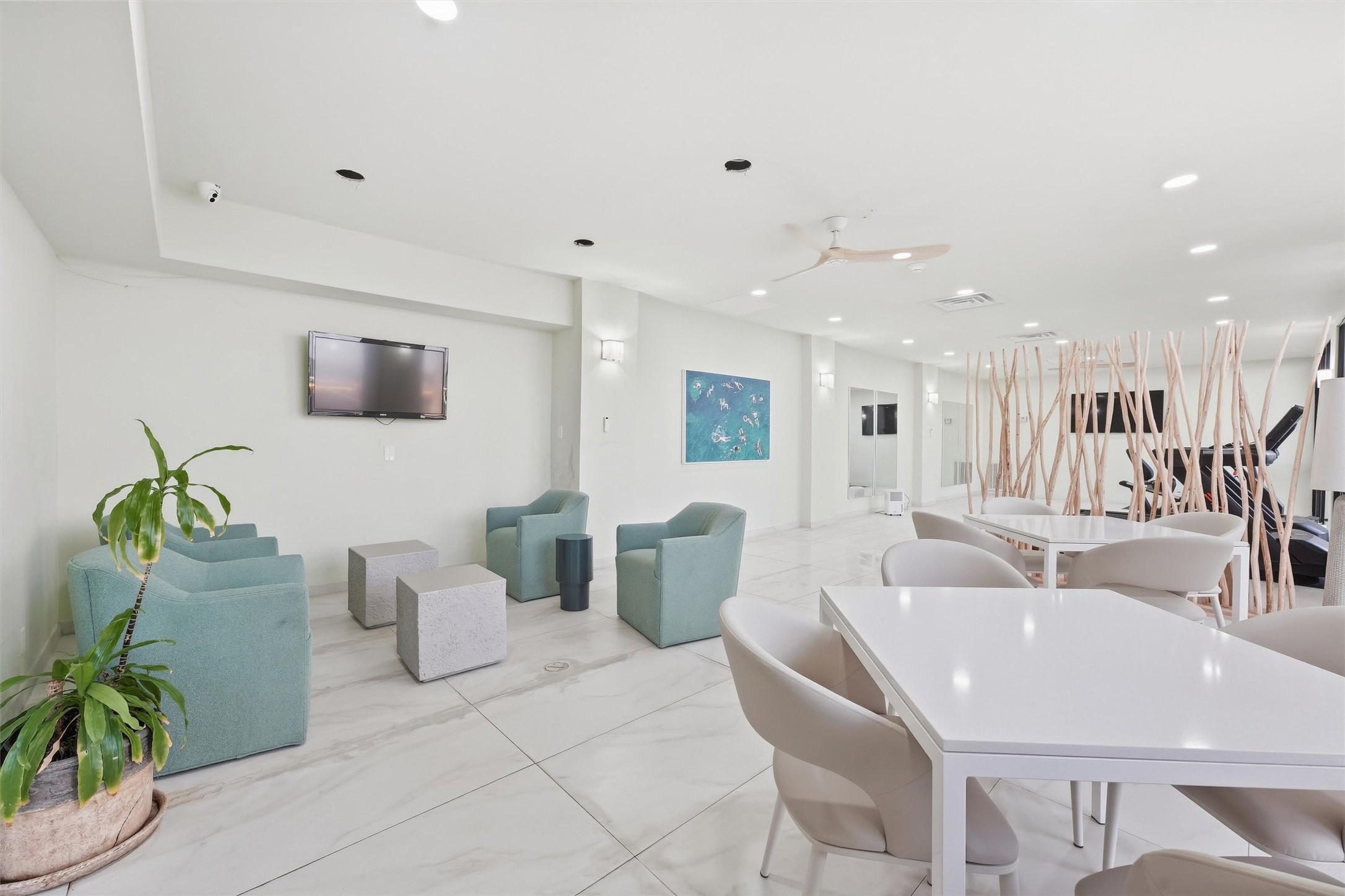Bright and modern communal space featuring comfortable seating, a wall-mounted TV, and stylish decor, perfect for relaxation or social gatherings.