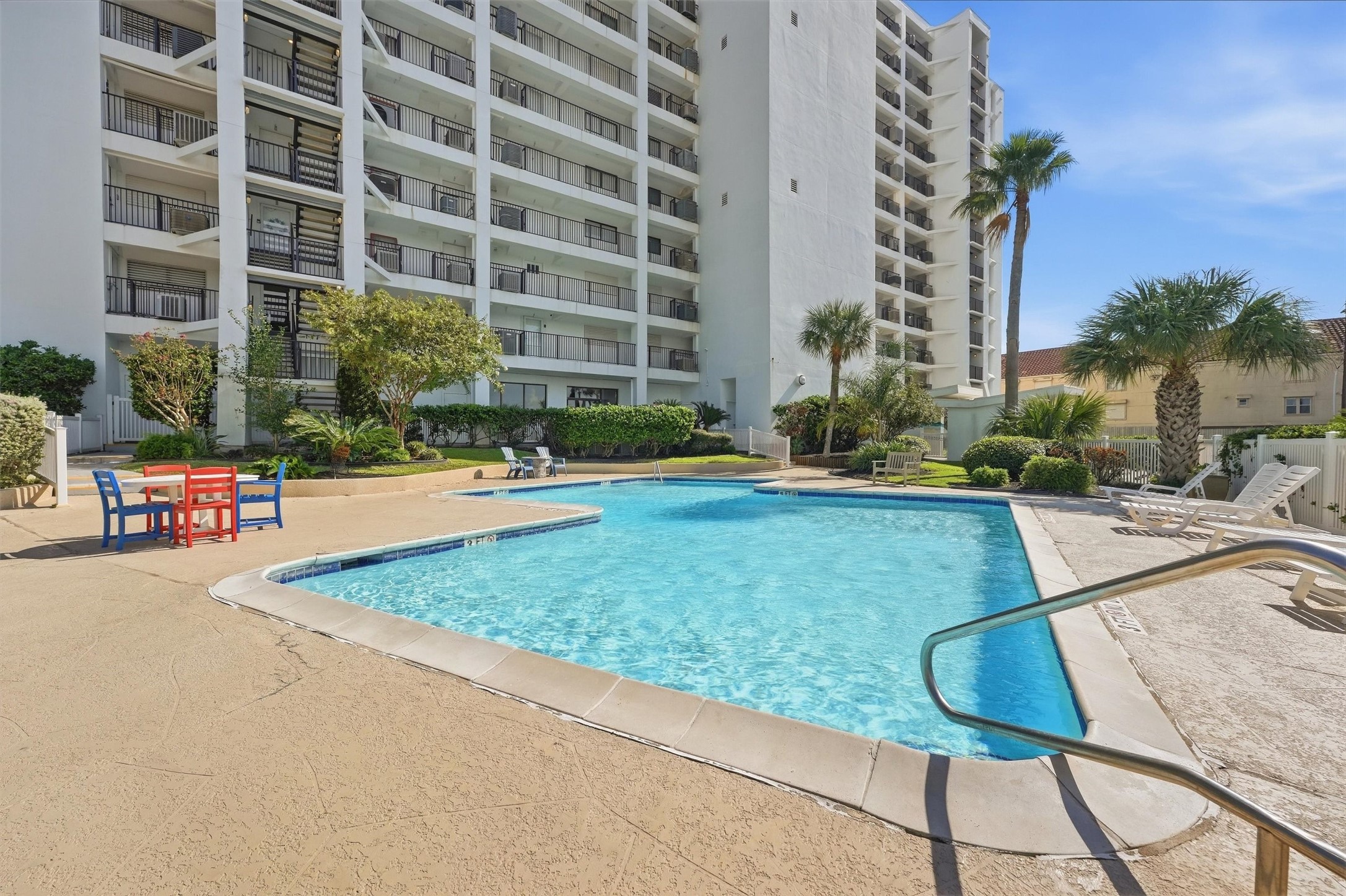 Enjoy resort-style living with this inviting outdoor pool area, surrounded by lush landscaping and ample seating, perfect for relaxation and entertaining.