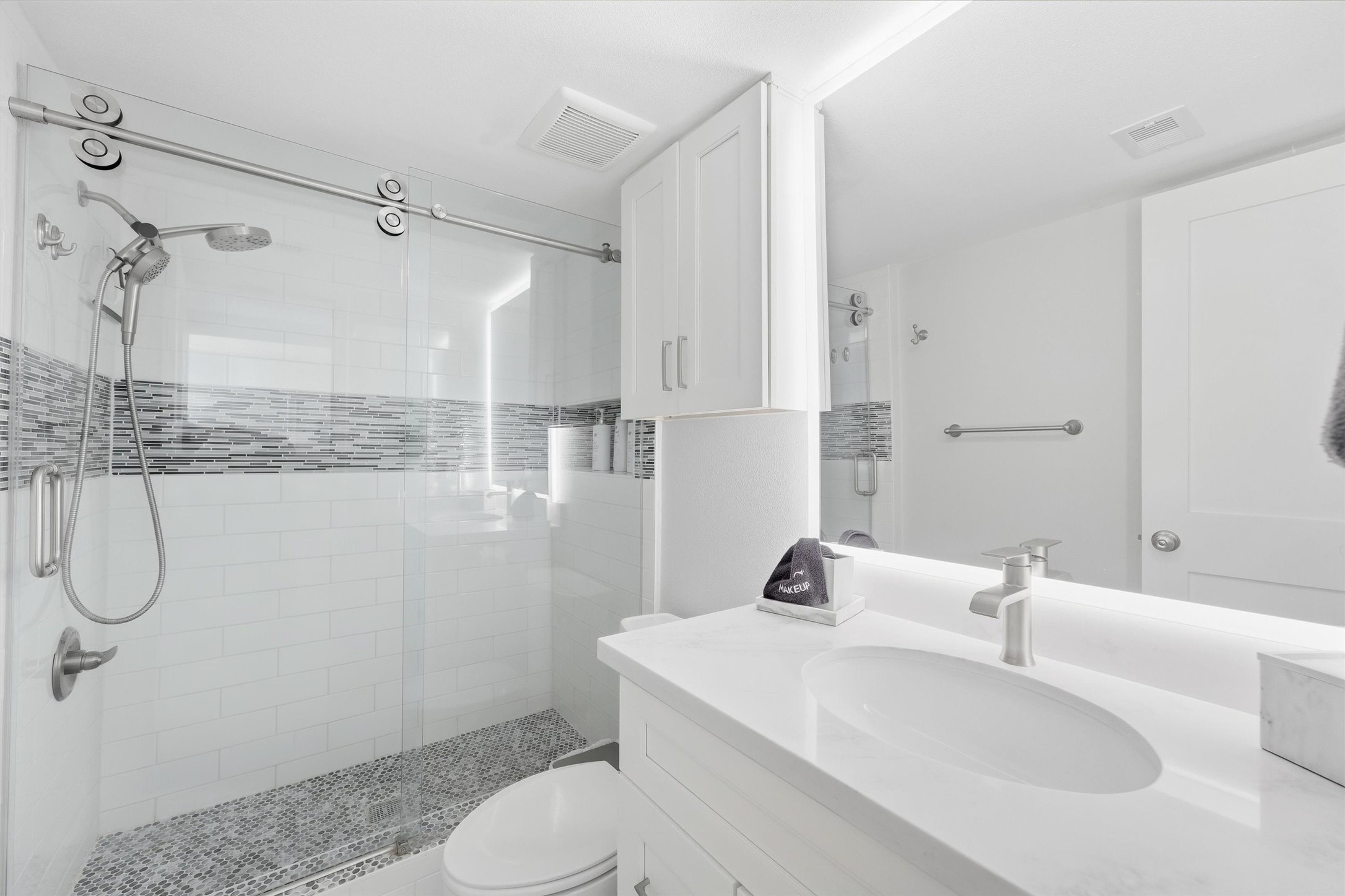 Stylish bathroom featuring a sleek glass-enclosed shower with modern tile accents, elegant fixtures, and a pristine white vanity for a refreshing, contemporary feel.
