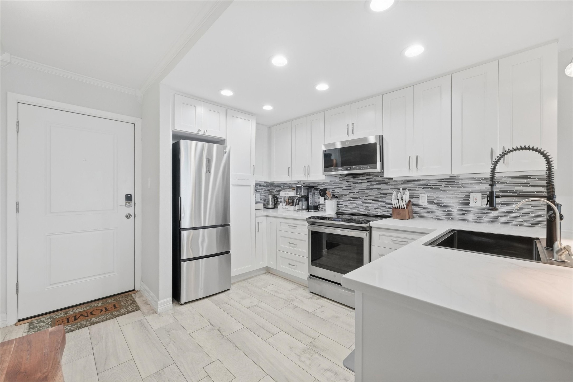 Modern kitchen with sleek white cabinetry, stainless steel appliances, and a stylish tile backsplash, offering a bright and inviting space.