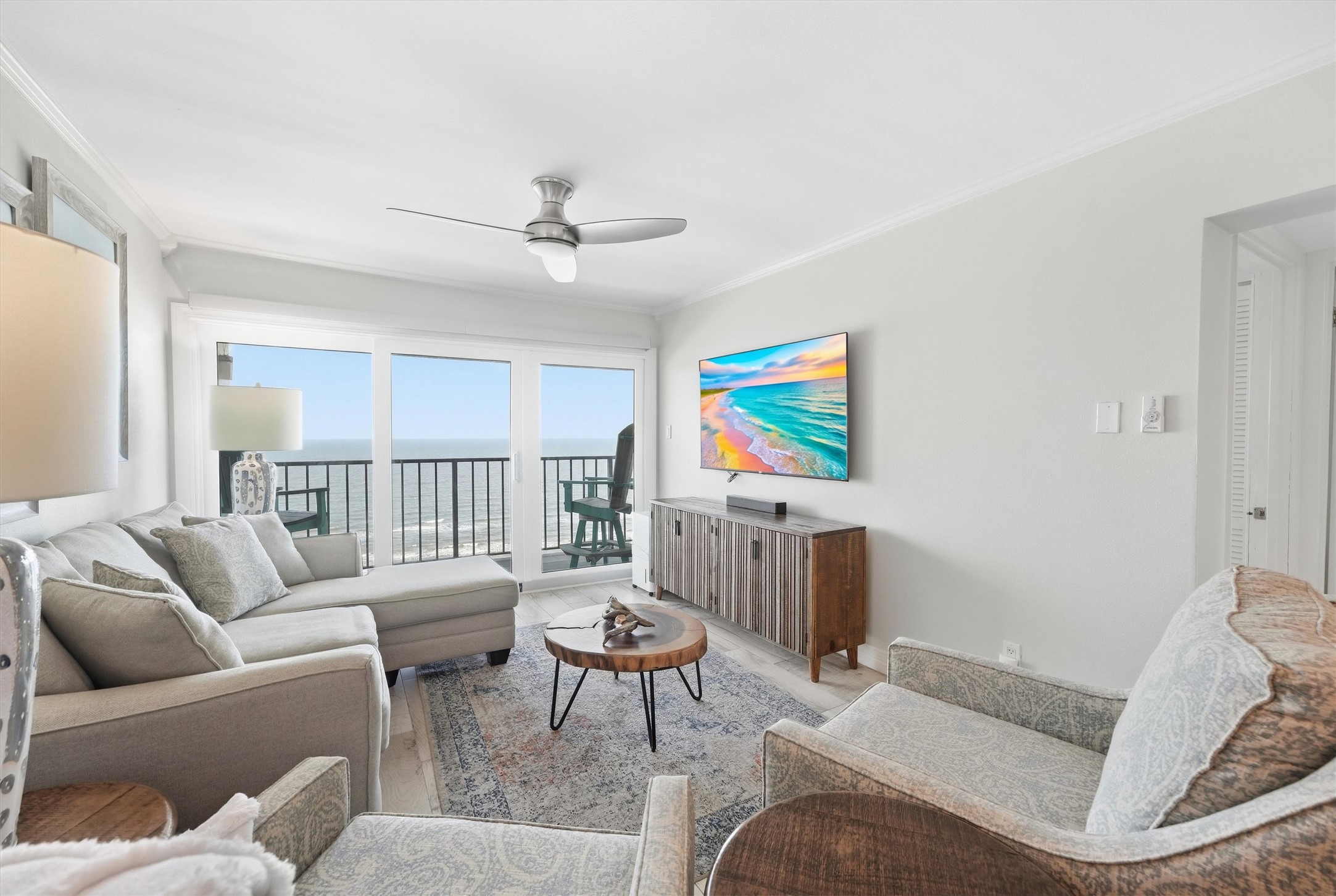 Bright and airy living room with ocean views, featuring a comfortable sectional, stylish armchairs, and a modern ceiling fan. Bright and airy living room with ocean views, featuring a comfortable sectional, stylish armchairs, and a modern ceiling fan.