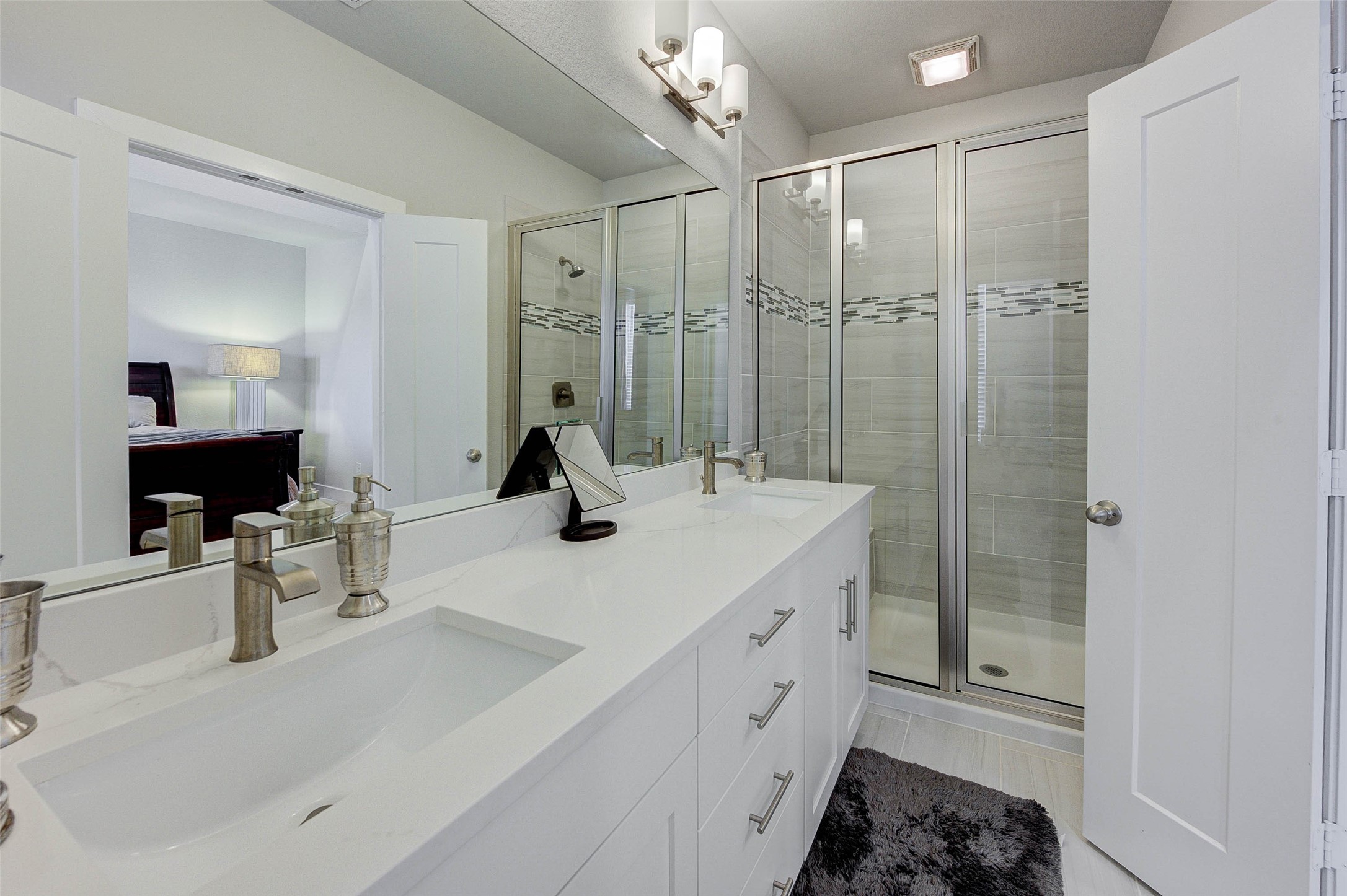 Modern bathroom with dual sinks, sleek fixtures, and a spacious glass-enclosed shower. Bright lighting and a neutral color palette create a clean, inviting atmosphere.