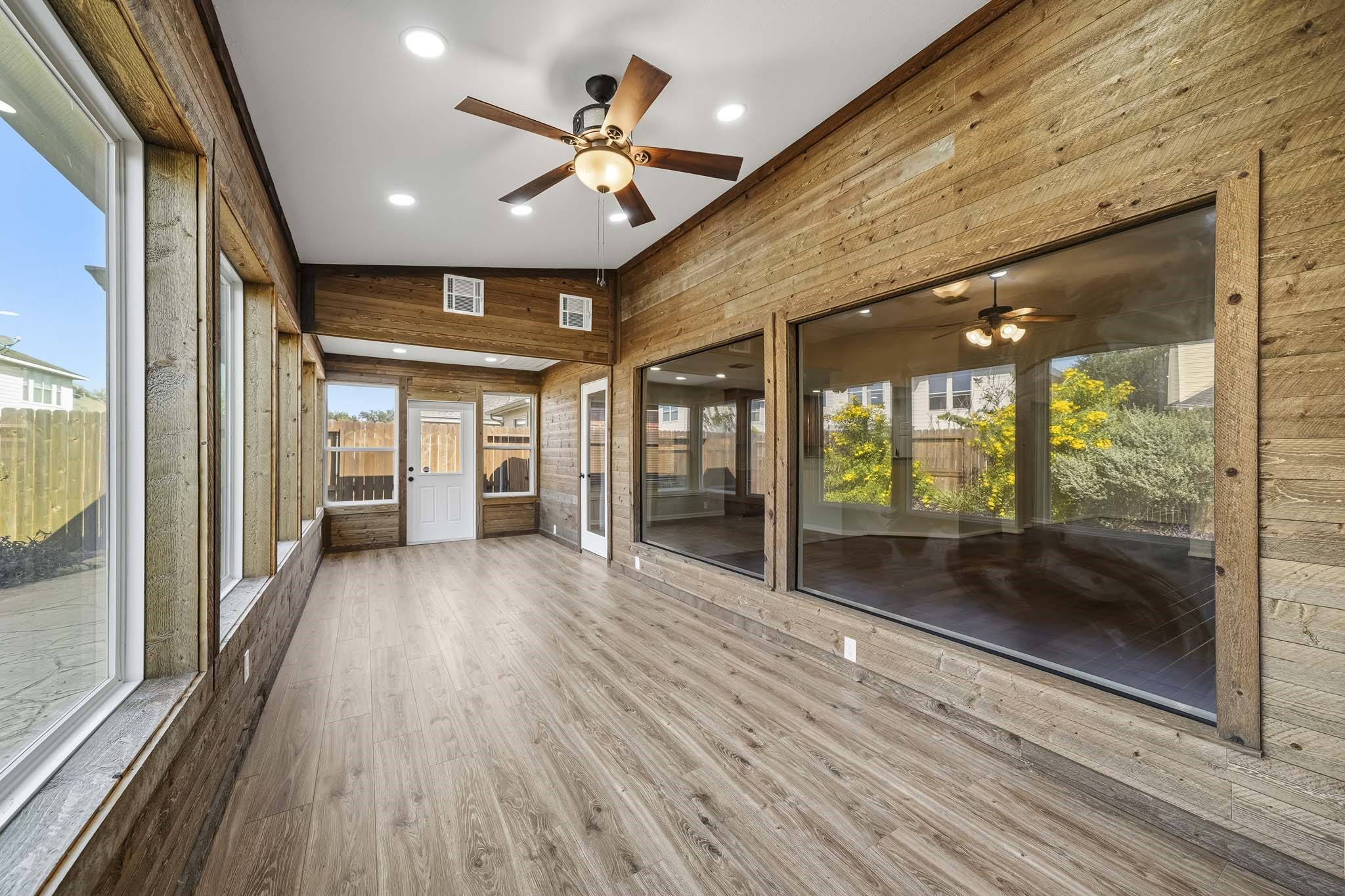 Sun room finished with wood walls and large windows adds warmth to this bonus space, creating a cozy and inviting atmosphere perfect for relaxation or entertaining.