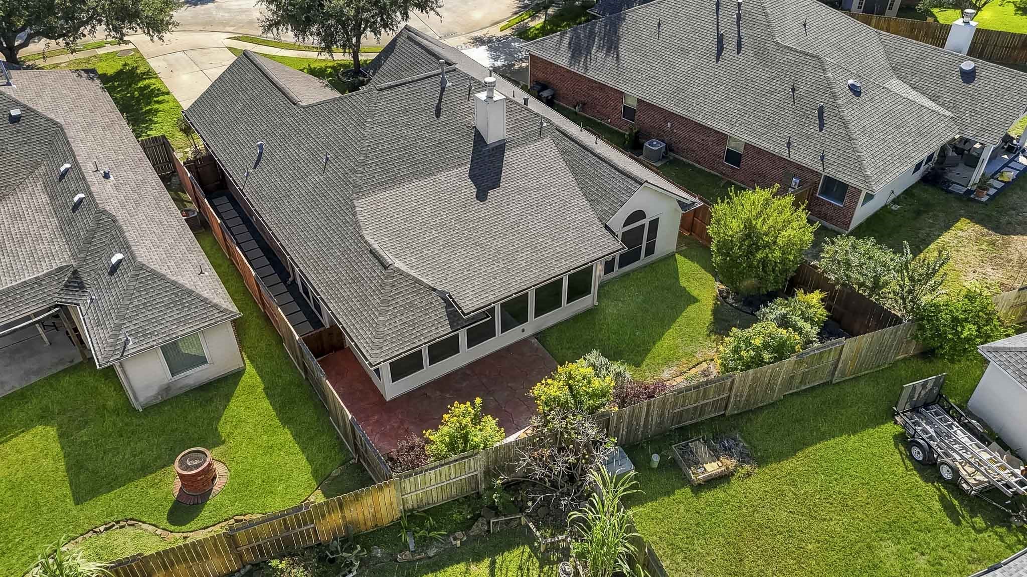 Aerial view of this one-story residence showcasing the full property layout, backyard, and surrounding neighborhood.