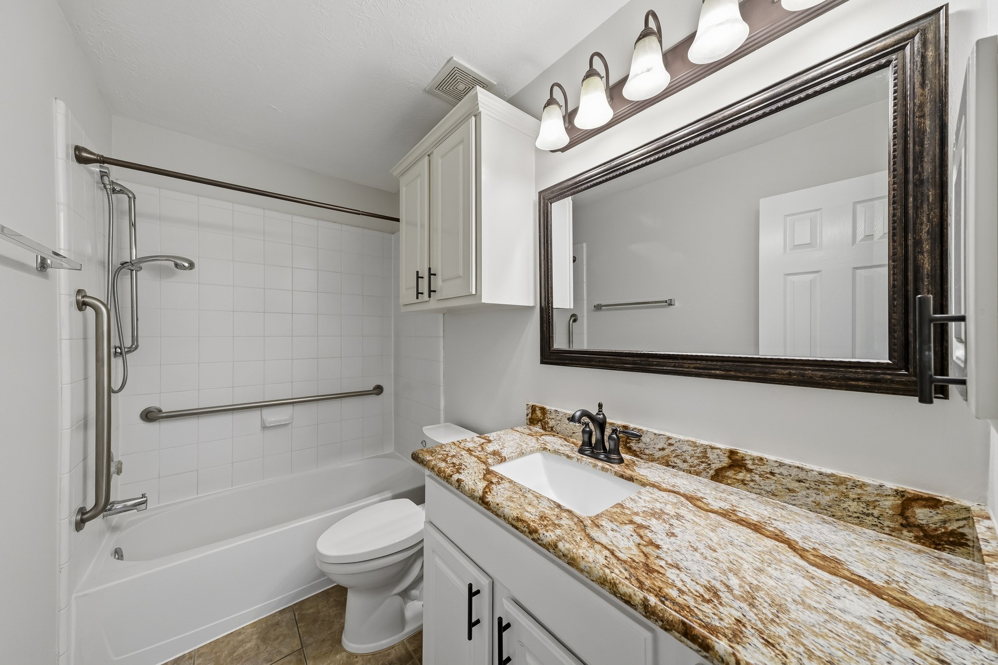 Secondary bathroom featuring updated lighting fixtures, elegant granite countertops, and a contemporary vanity mirror.