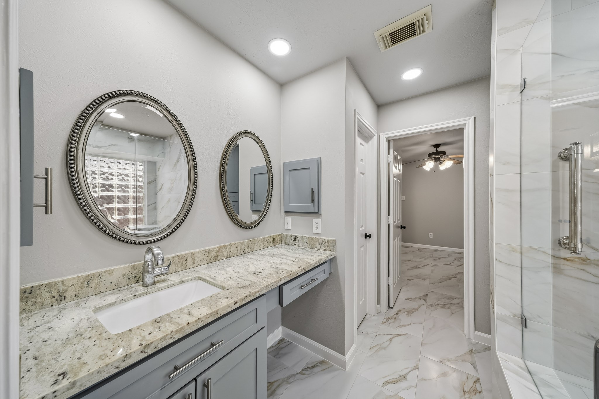 The space boasts an expansive vanity providing an abundance of smart storage solutions to keep your countertops clutter-free. Every detail has been thoughtfully selected, from the sleek, elegant hardware that adds a sophisticated touch to the clean lines and modern finishes that define the room's contemporary aesthetic.