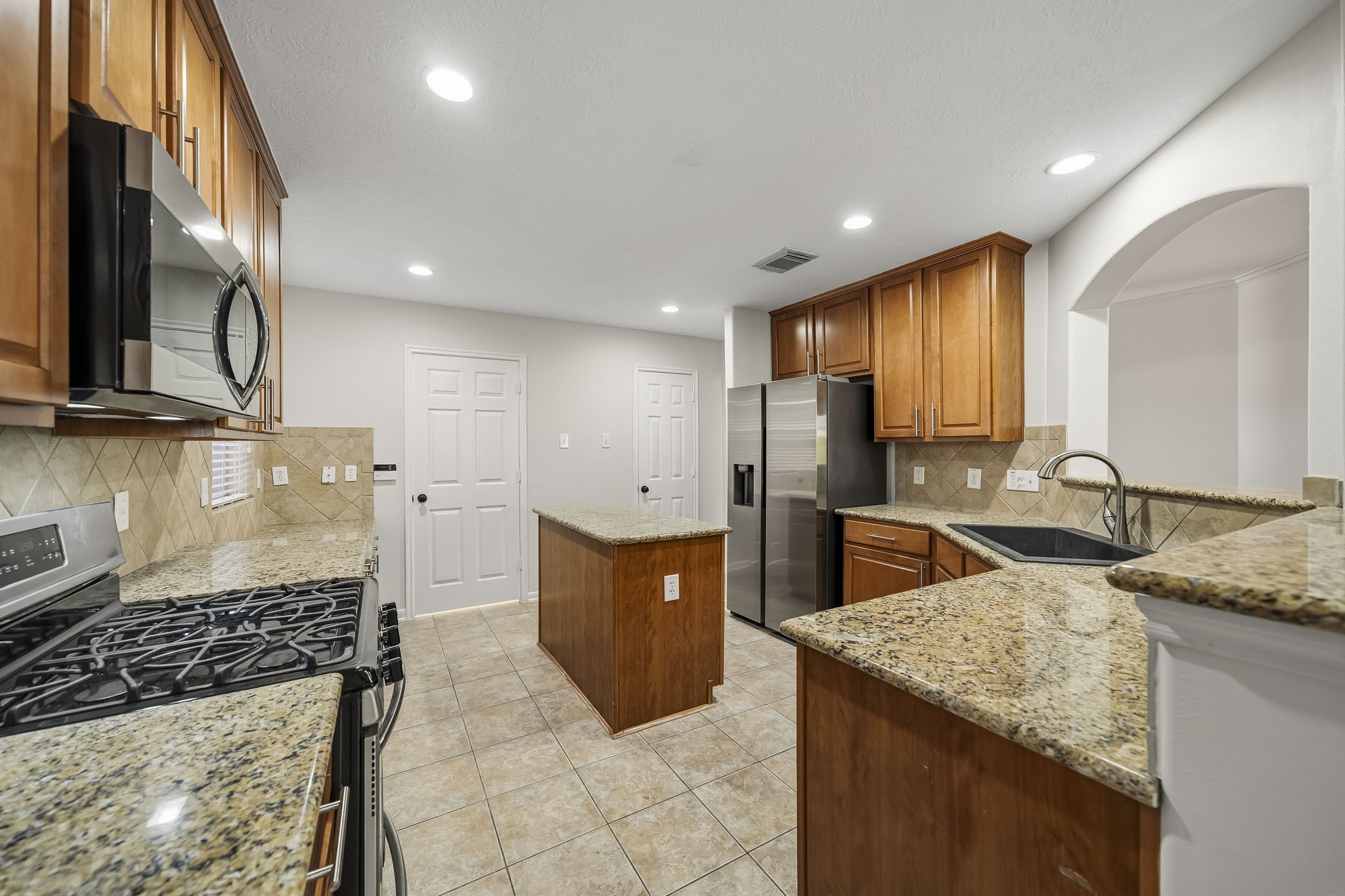 Lovely kitchen equipped with beautiful wood cabinetry, granite counters, and stainless steel appliances. This culinary space features high-end finishes and an open layout, perfect for both everyday meal preparation and entertaining guests.