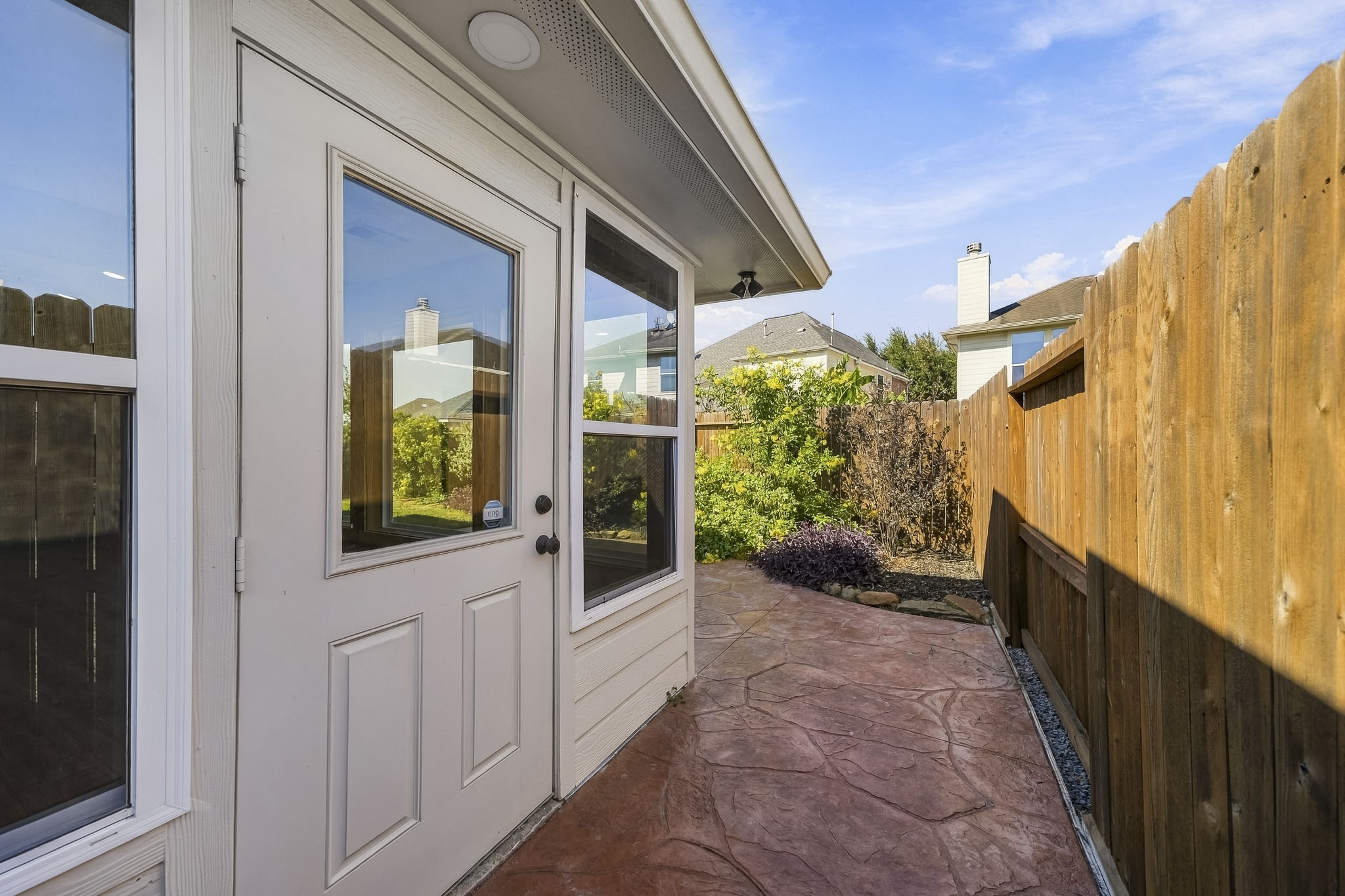 The side door provides convenient access to a beautifully finished stamped concrete patio, creating an inviting transition between your indoor living space and the outdoor backyard area, perfect for entertaining guests or enjoying a quiet morning coffee.