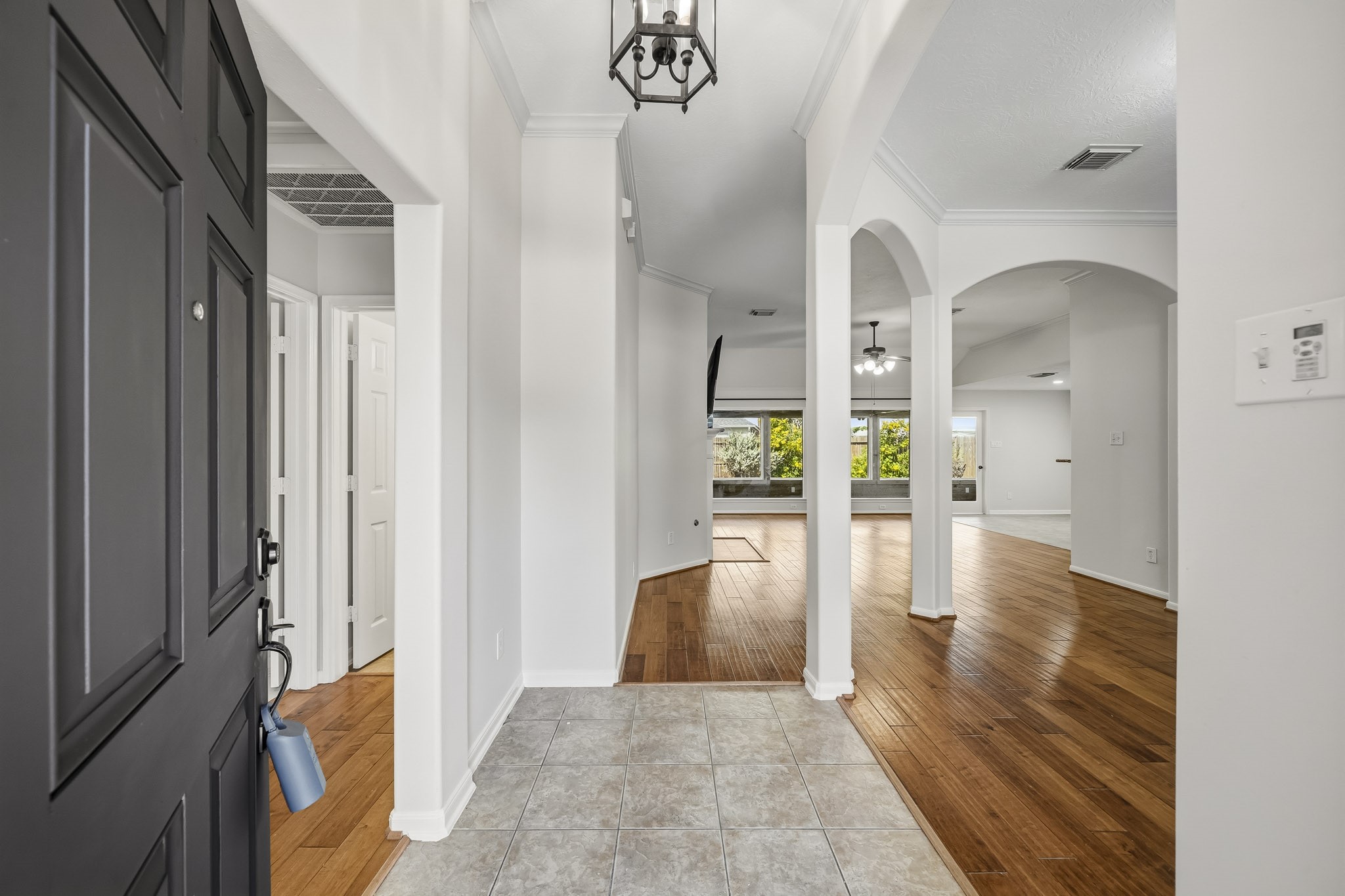 Formal entry featuring elegant architectural arches, a stunning chandelier, and gleaming hardwood floors, with a sophisticated dining room situated to the right. Formal entry featuring elegant architectural arches, a stunning chandelier, and gleaming hardwood floors, with a sophisticated dining room situated to the right.