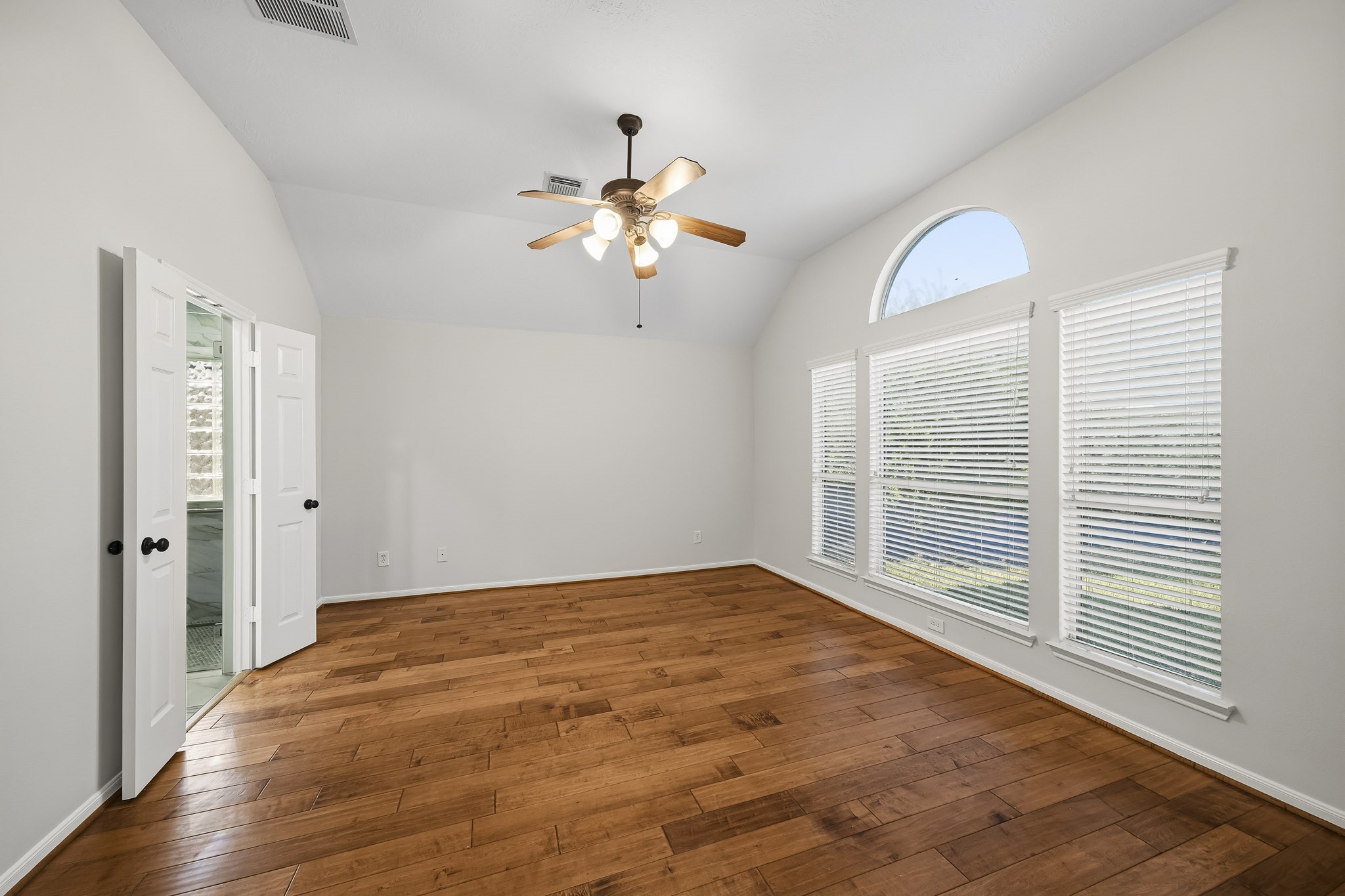 Elegant windows bring in natural light with a double door entrance into the reimagined primary bath. This spa-inspired retreat features sophisticated finishes, creating a bright and airy atmosphere perfect for relaxation.