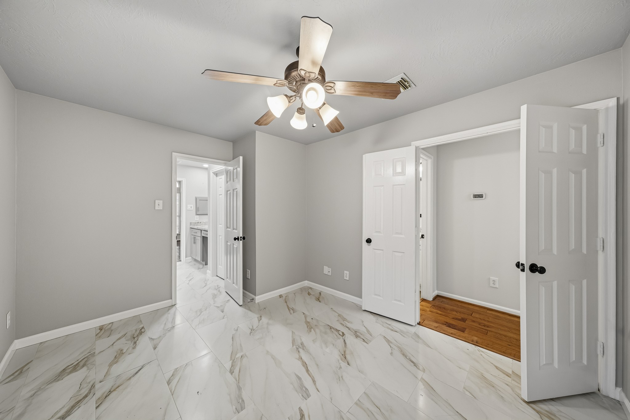 Sun-drenched home office featuring sophisticated double doors and an open layout that blends professional functionality with a seamless transition into the home's primary suite.