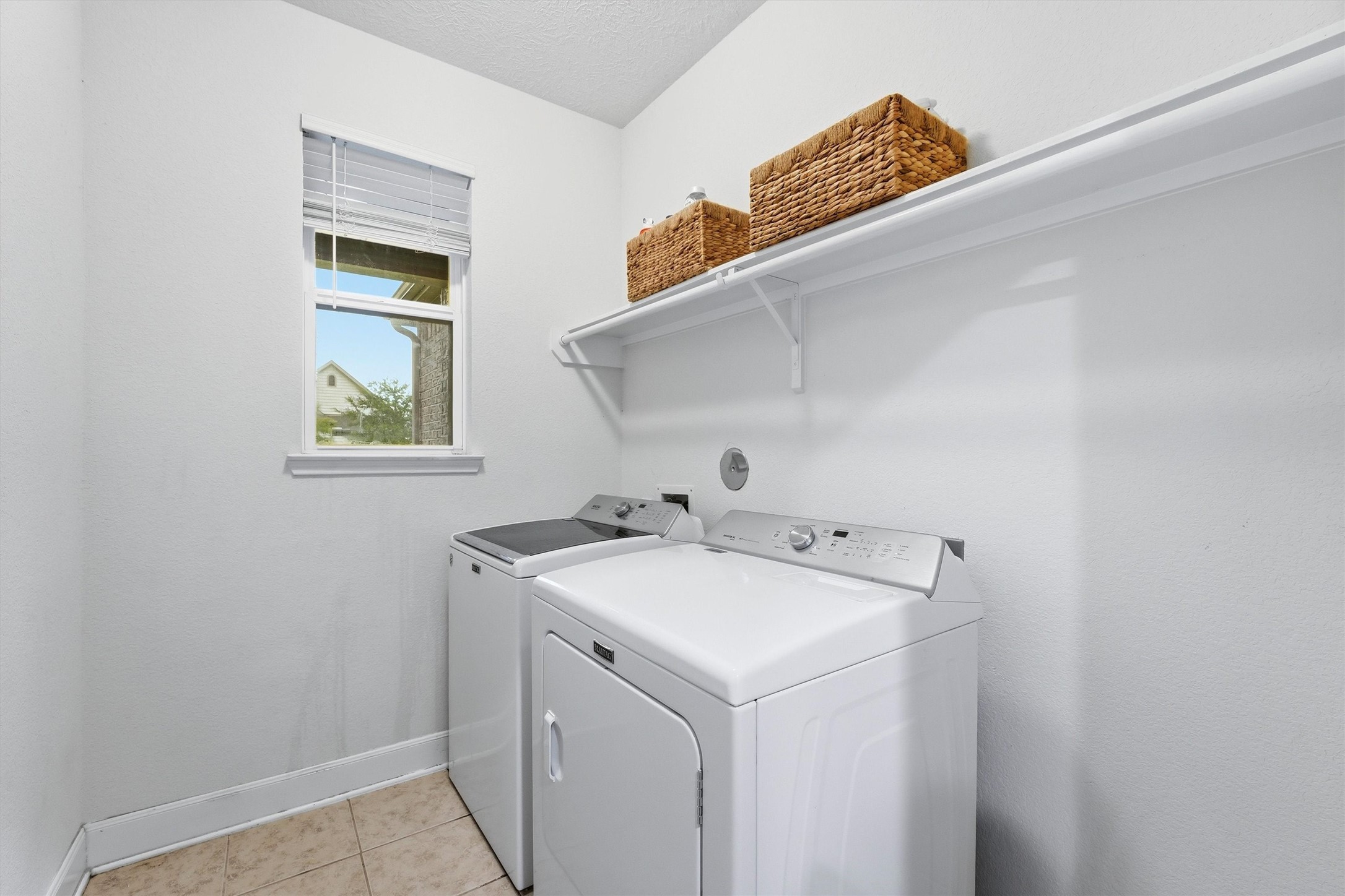 Convenient utility room with washer/dryer connections and overhead storage.