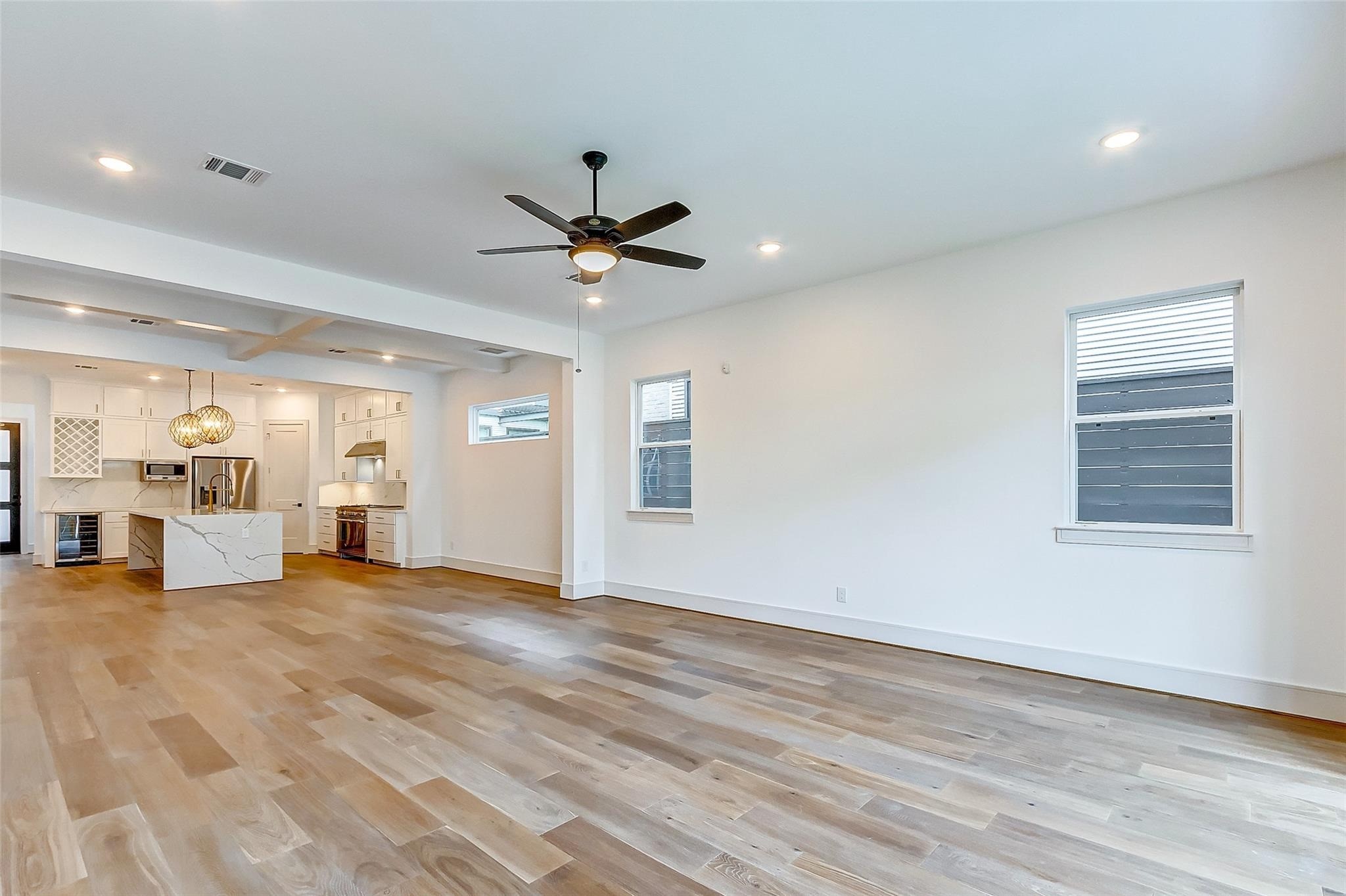 This family room/living room sits adjacent to the kitchen and is SPACIOUS! Features include designer paint, tall ceilings, a modern ceiling fan, bright windows, and hardwood floors. This family room/living room sits adjacent to the kitchen and is SPACIOUS! Features include designer paint, tall ceilings, a modern ceiling fan, bright windows, and hardwood floors.