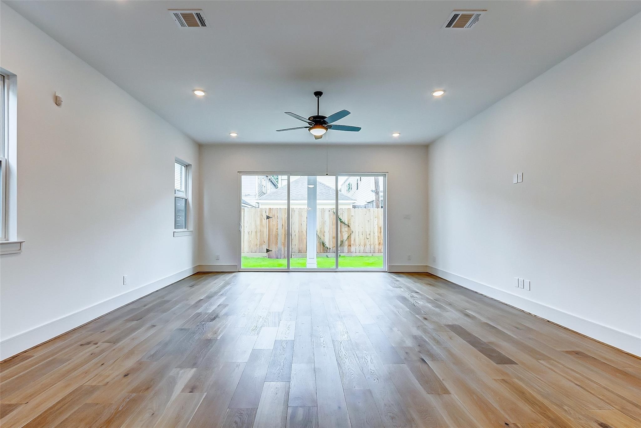 The spacious living room opens up to the private fenced backyard through large sliding glass doors.
