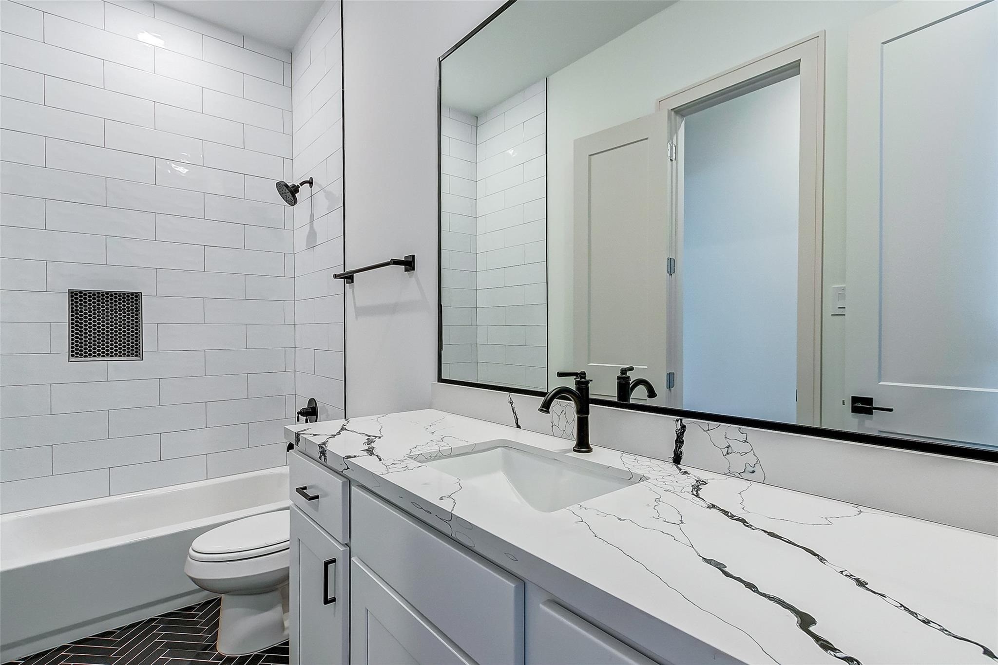 Elegant bathroom featuring a sleek black and white design, with a spacious countertop, modern fixtures, and a stylish tiled shower for a touch of luxury.