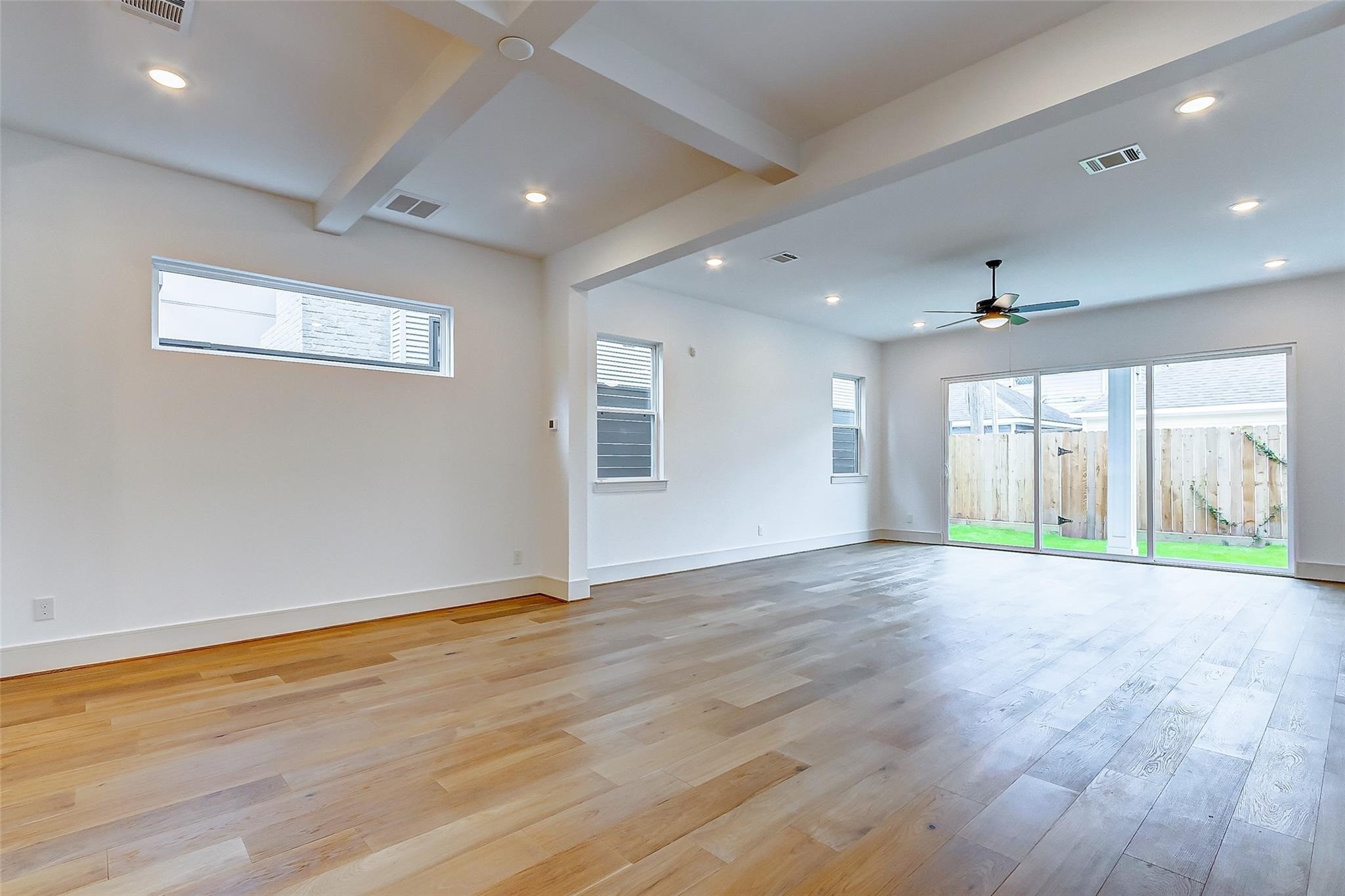 Spacious open-concept living area with elegant hardwood floors, recessed lighting, and abundant natural light from large sliding glass doors leading to the backyard/patio. Spacious open-concept living area with elegant hardwood floors, recessed lighting, and abundant natural light from large sliding glass doors leading to the backyard/patio.