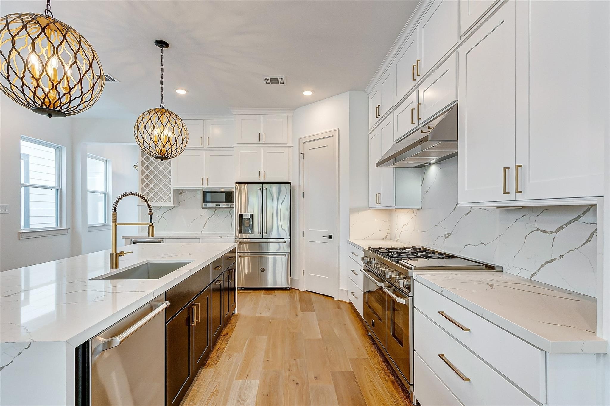 Stunning chefs kitchen showcasing sleek white cabinetry, elegant quartz countertops, and state-of-the-art stainless steel high end appliances. The space is illuminated by stylish pendant lighting, complementing the warm wood flooring and sophisticated design. Stunning chefs kitchen showcasing sleek white cabinetry, elegant quartz countertops, and state-of-the-art stainless steel high end appliances. The space is illuminated by stylish pendant lighting, complementing the warm wood flooring and sophisticated design.