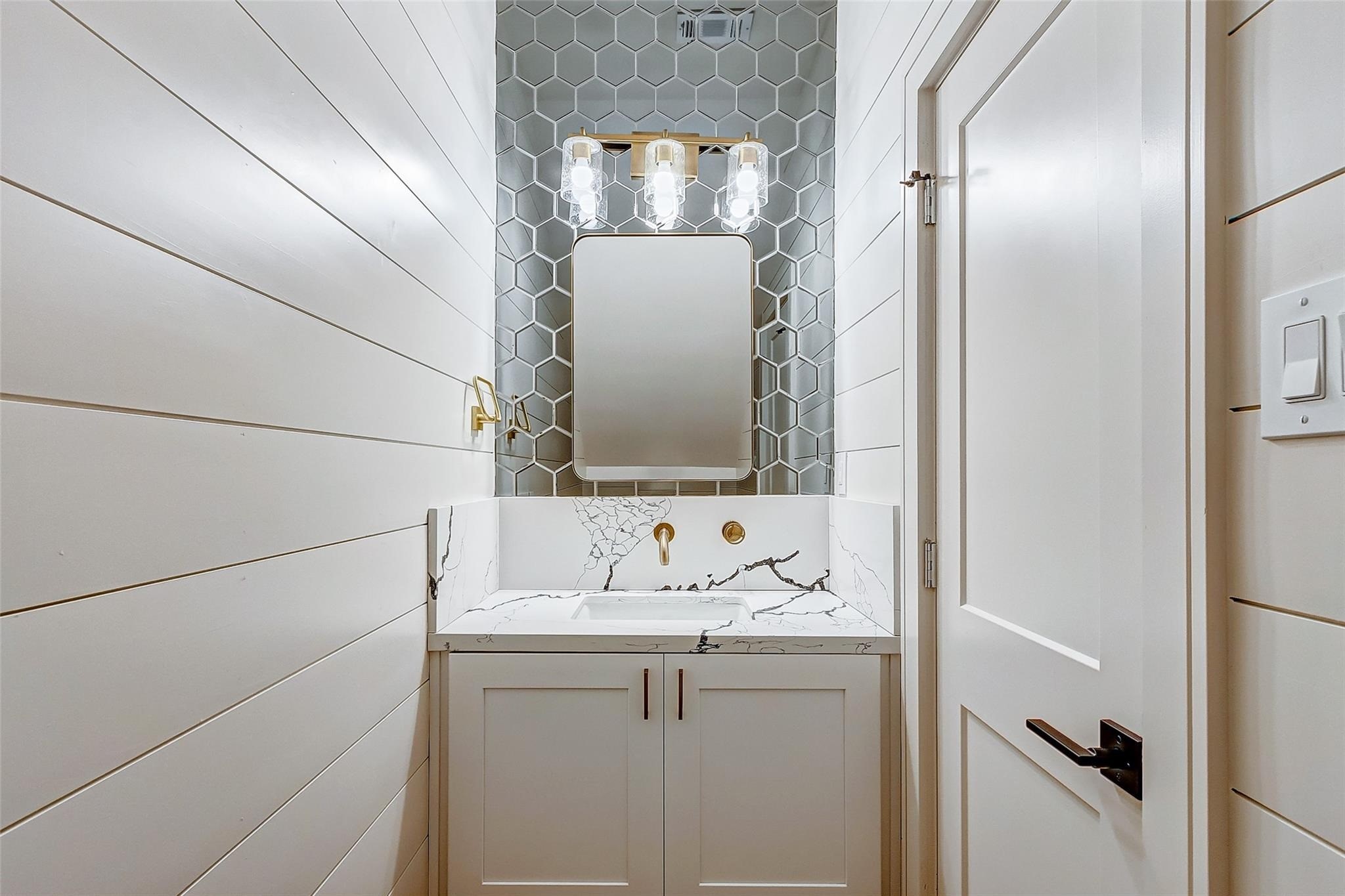 Sophisticated powder room/ guest bathroom with elegant shiplap walls, a chic hexagonal tile backsplash, and a modern vanity featuring a sleek quartz countertop.