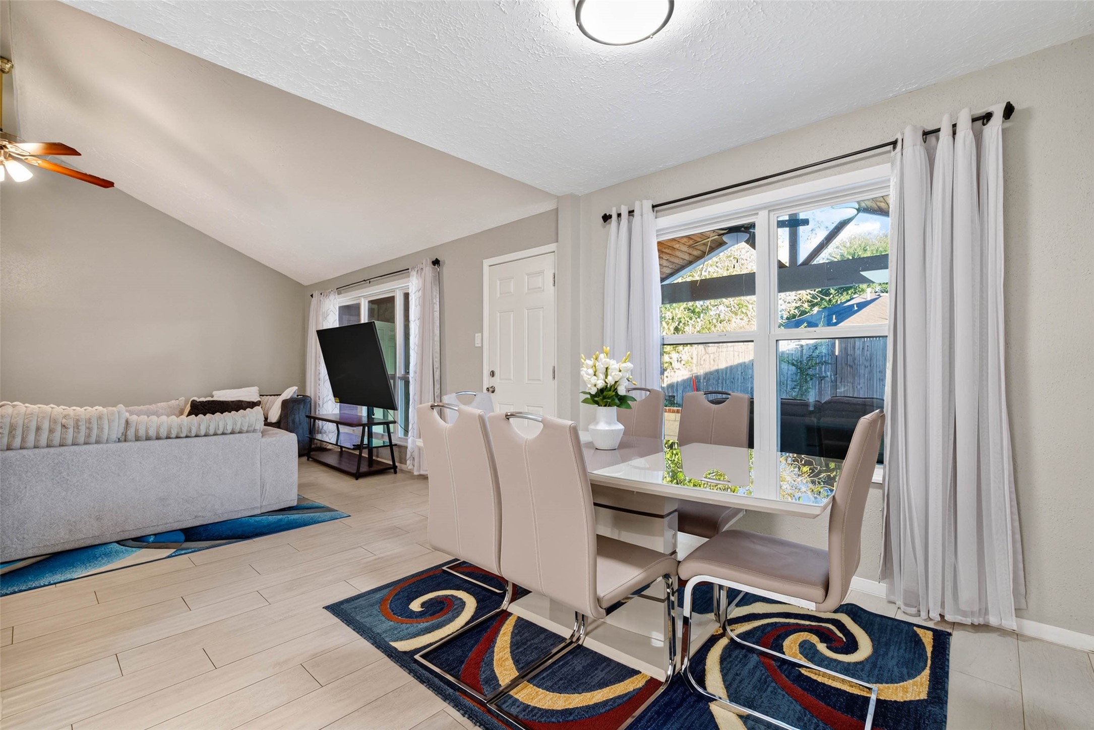 View of the dining room with a window that allows you to look at the backyard patio and the living room.