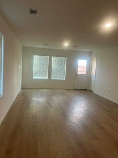 Spacious living area with abundant natural light, featuring hardwood floors, recessed lighting, and large windows.