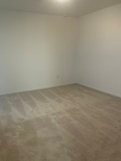 Spacious room with neutral walls and plush carpeting, perfect for creating a cozy retreat.