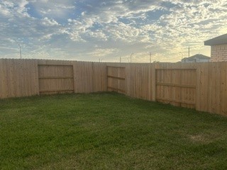 Spacious backyard with lush green grass and a sturdy wooden fence, perfect for relaxation and outdoor activities.