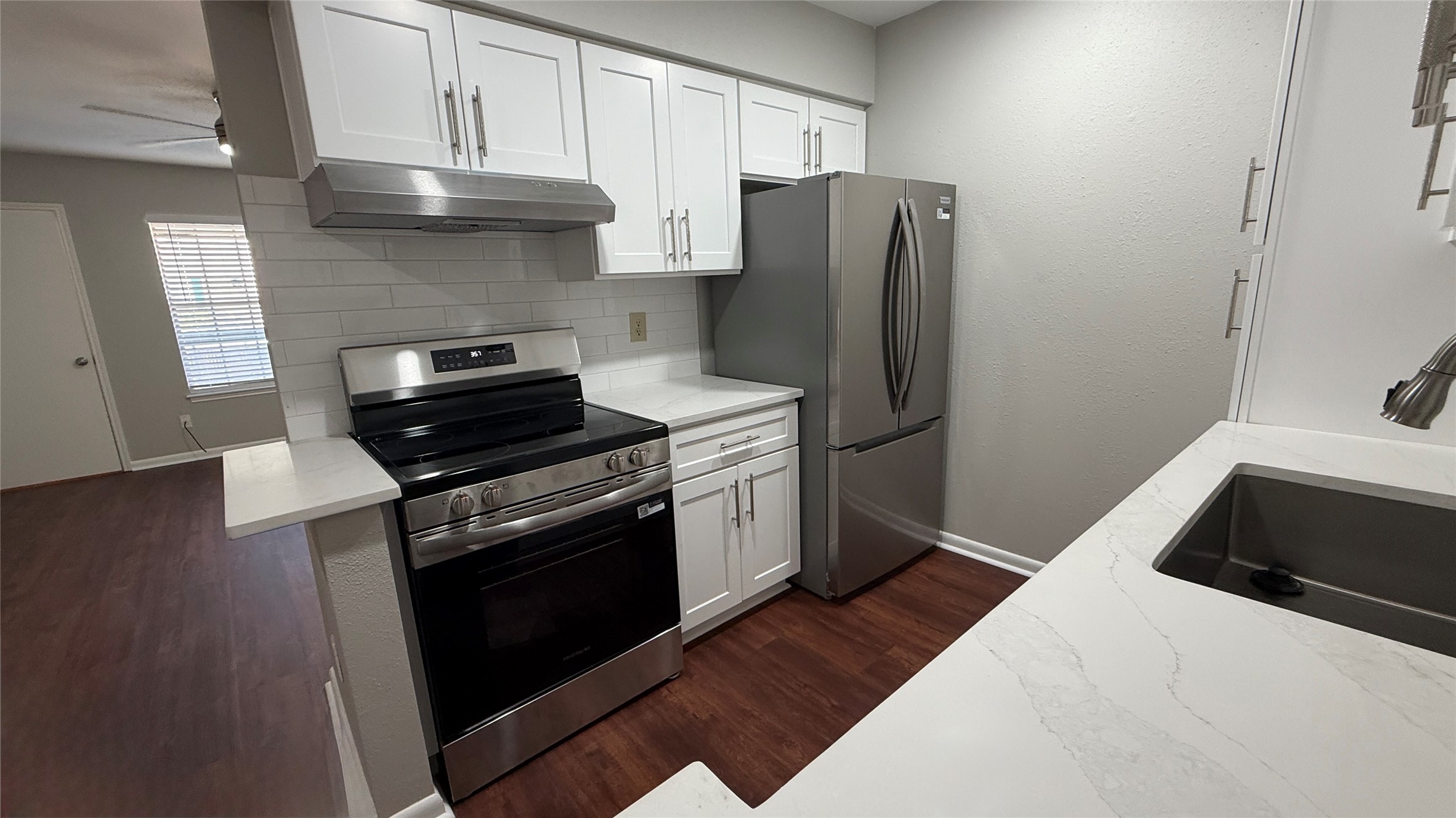 Modern stainless steel range, refrigerator, and sleek countertops complement the bright, updated cabinetry.