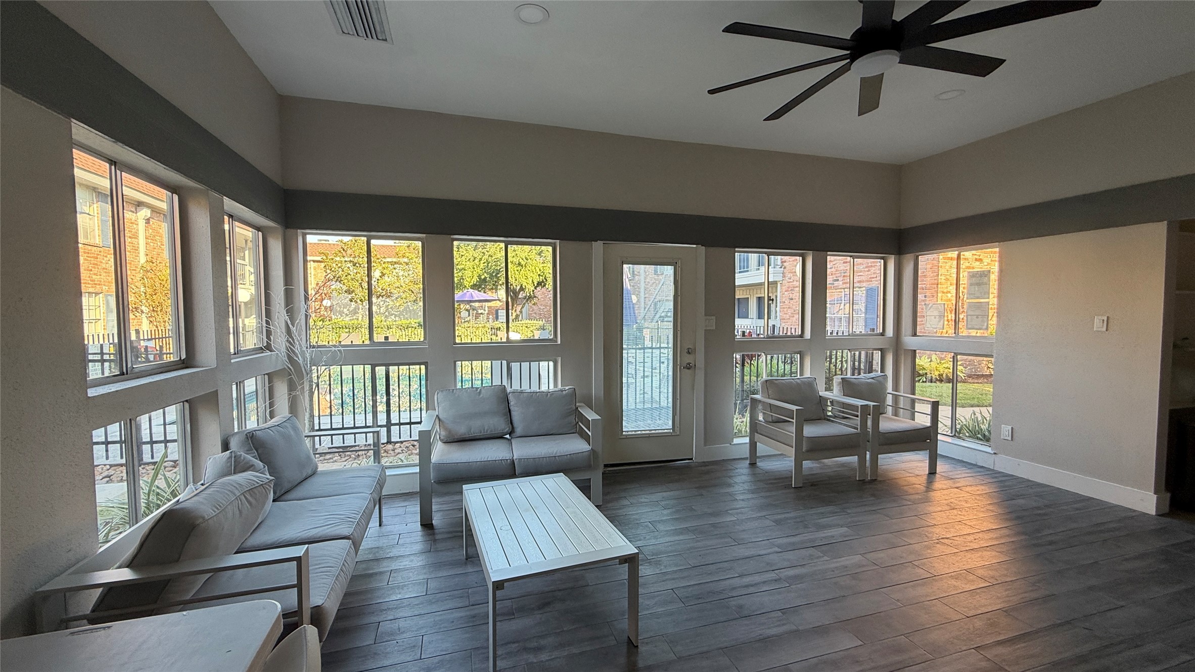 Welcoming clubhouse gathering space featuring abundant windows, comfortable seating, and views of the landscaped grounds.