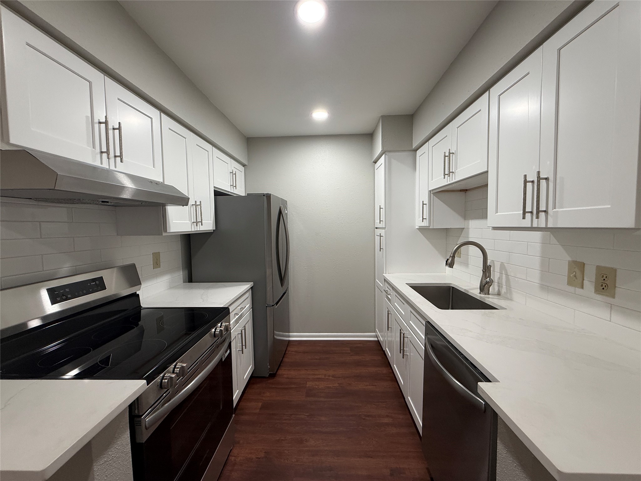 Beautifully updated galley kitchen featuring white shaker-style cabinetry, subway tile backsplash, and stainless steel appliances.