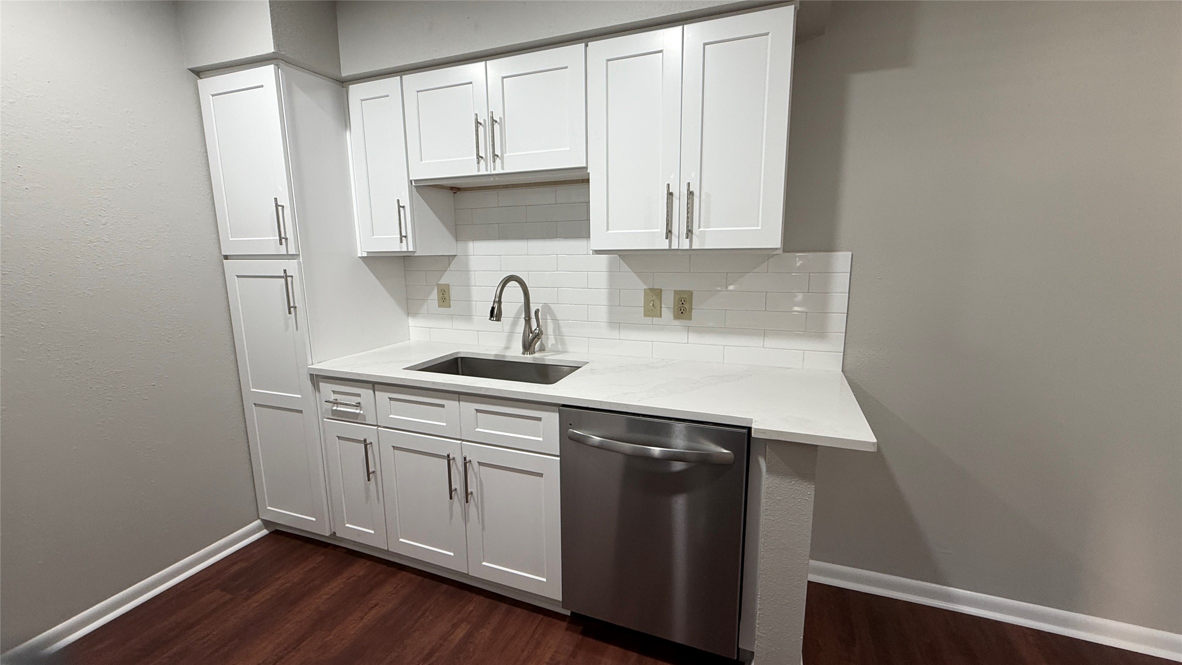 Generous countertop space, stainless steel sink, updated cabinetry, and dishwasher create a functional kitchen workspace.
