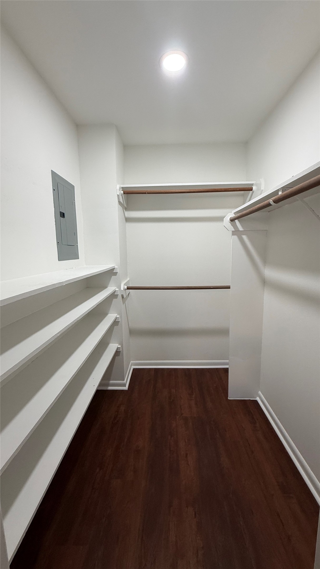 Spacious walk-in closet featuring built-in shelving and multiple hanging areas for organized storage.