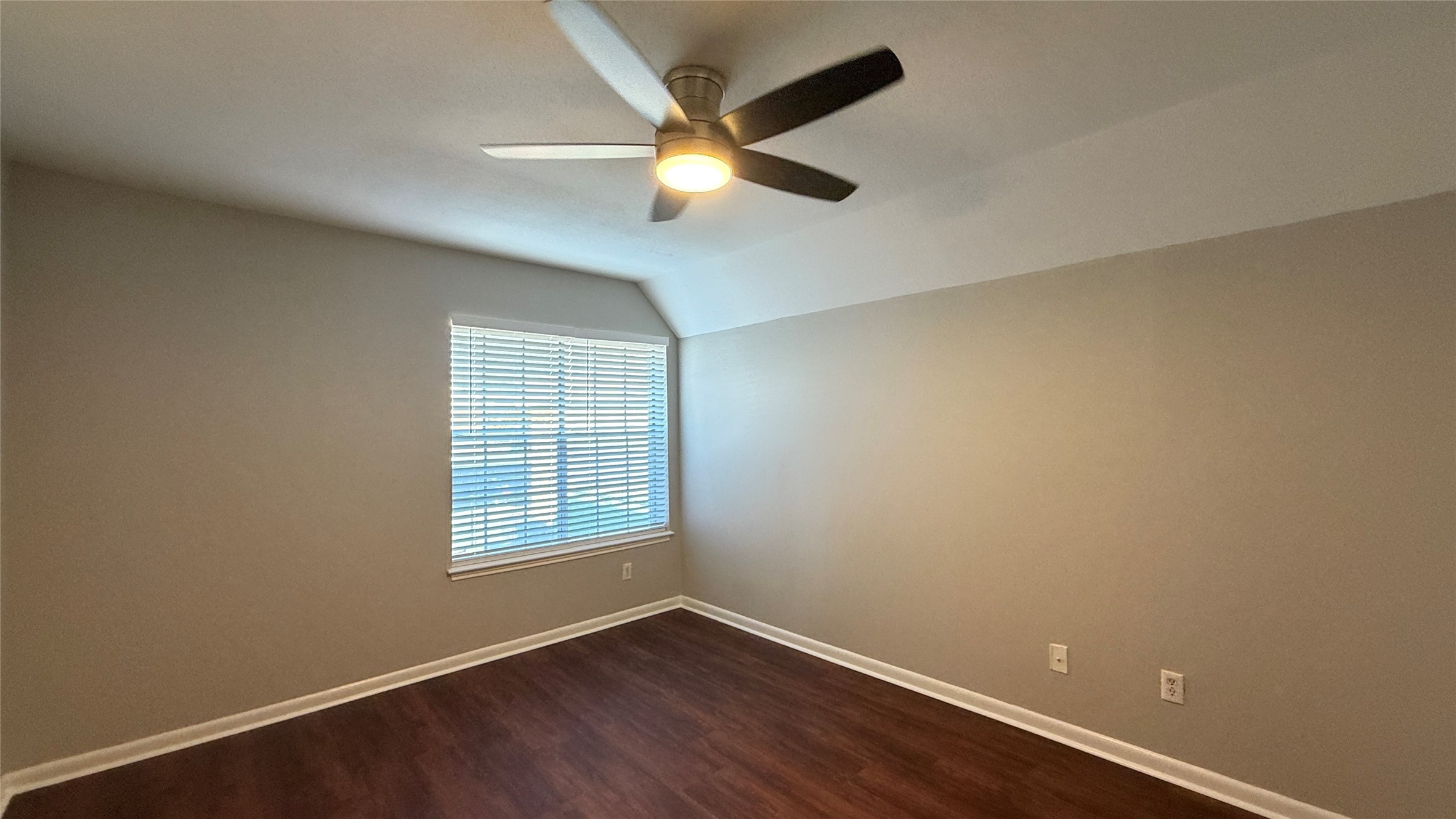 Comfortable bedroom featuring warm vinyl plank flooring, neutral tones, ceiling fan, and natural light.