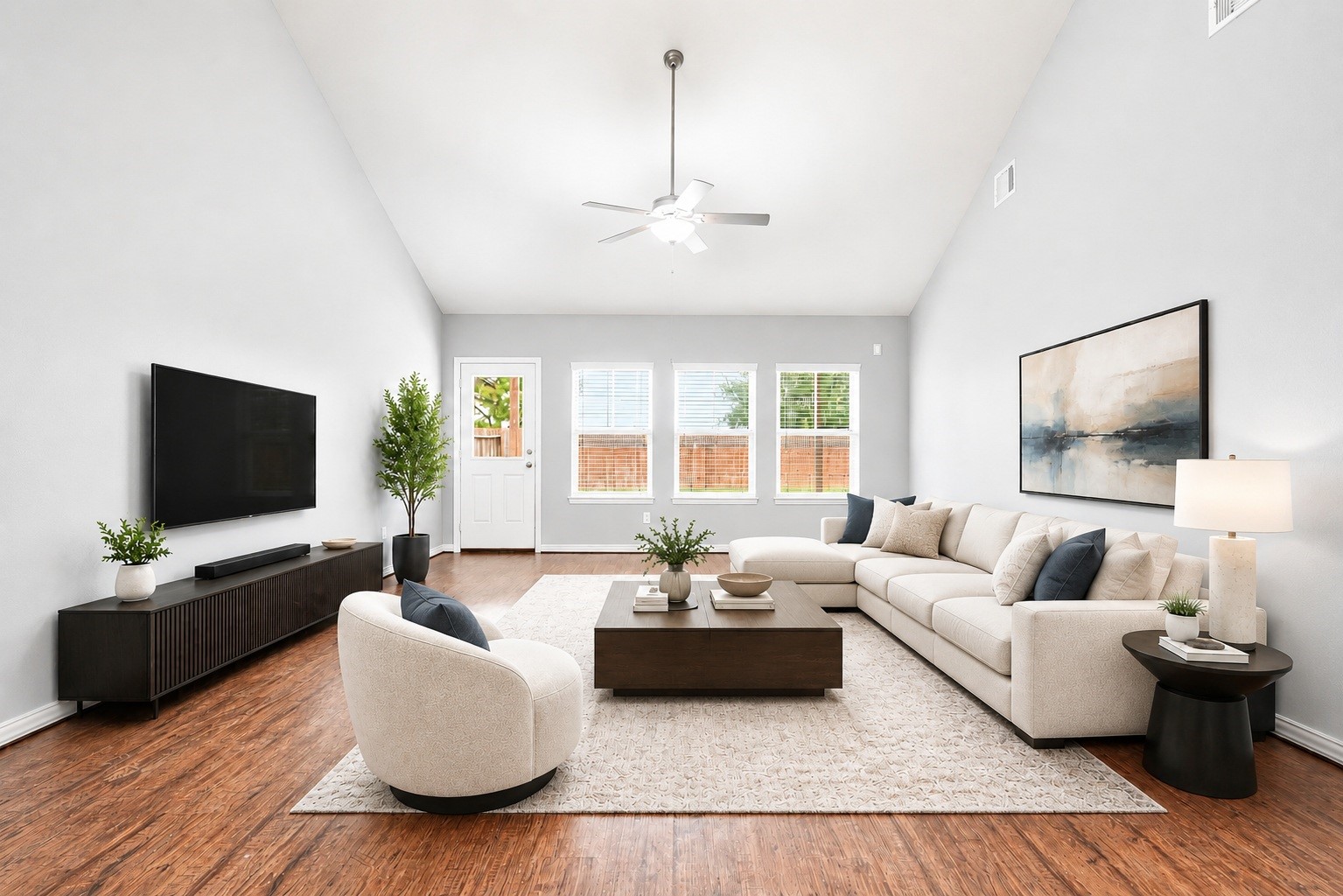 The living room features dramatic high ceilings, central ceiling fan cooling, a wall of windows framing backyard views, and a half-lite door providing quick access to the backyard. Virtually staged.