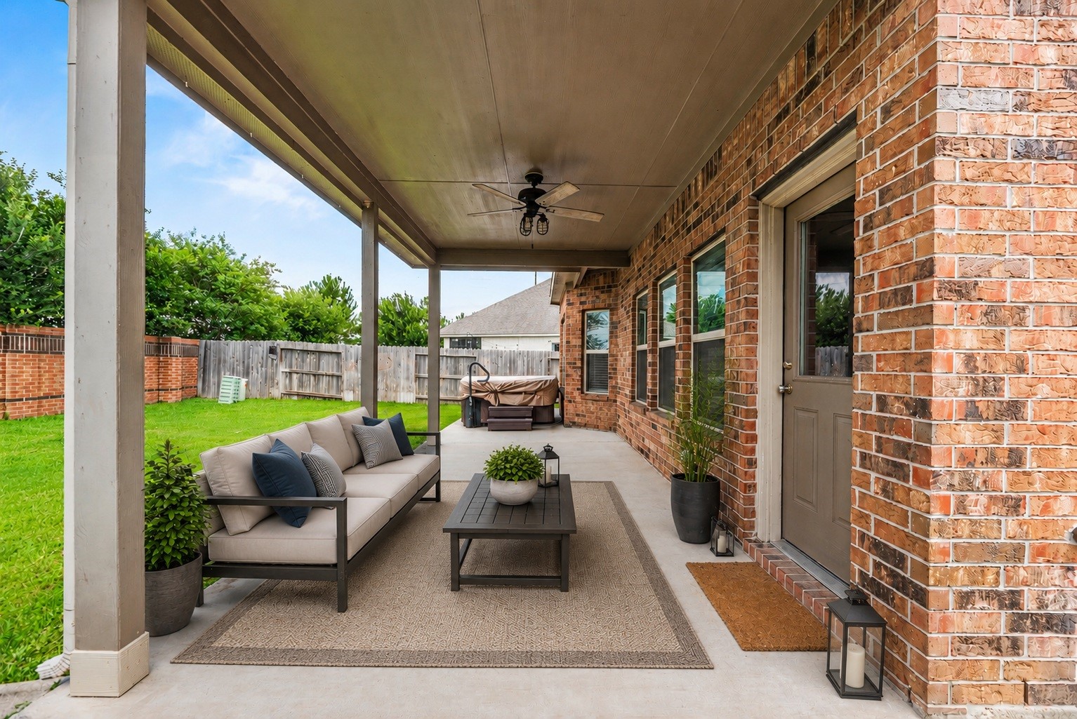 The outdoor entertaining area features a deep concrete covered patio complete with an outdoor ceiling fan, providing a cool, shaded environment for open-air dining and relaxation. Virtually staged.