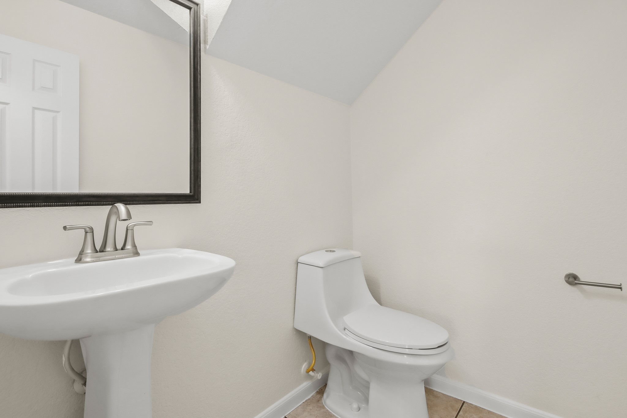 Beautifully appointed half bathroom, featuring a decorative mirror.